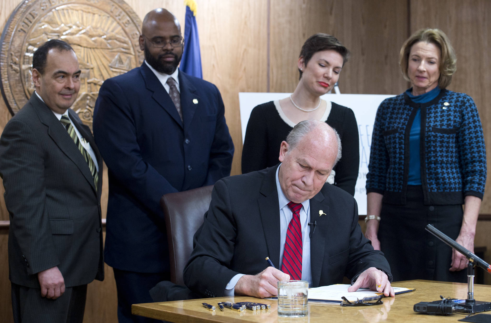 Gov. Bill Walker signs SB 91 in front of Sen. Donald Olson, D-Golovin, left, Sen. David Wilson, R-Wasilla, Rep. Ivy Spohnholz, D-Anchorage, and Sen. Cathy Giessel, R-Anchorage, in his Capitol conference room on Tuesday, March 21, 2017. The bill authorizes the chief medical officer of the Department of Health and Social Services to issue a standing order for the prescription of an opioid overdose drug. (Michael Penn | Juneau Empire)