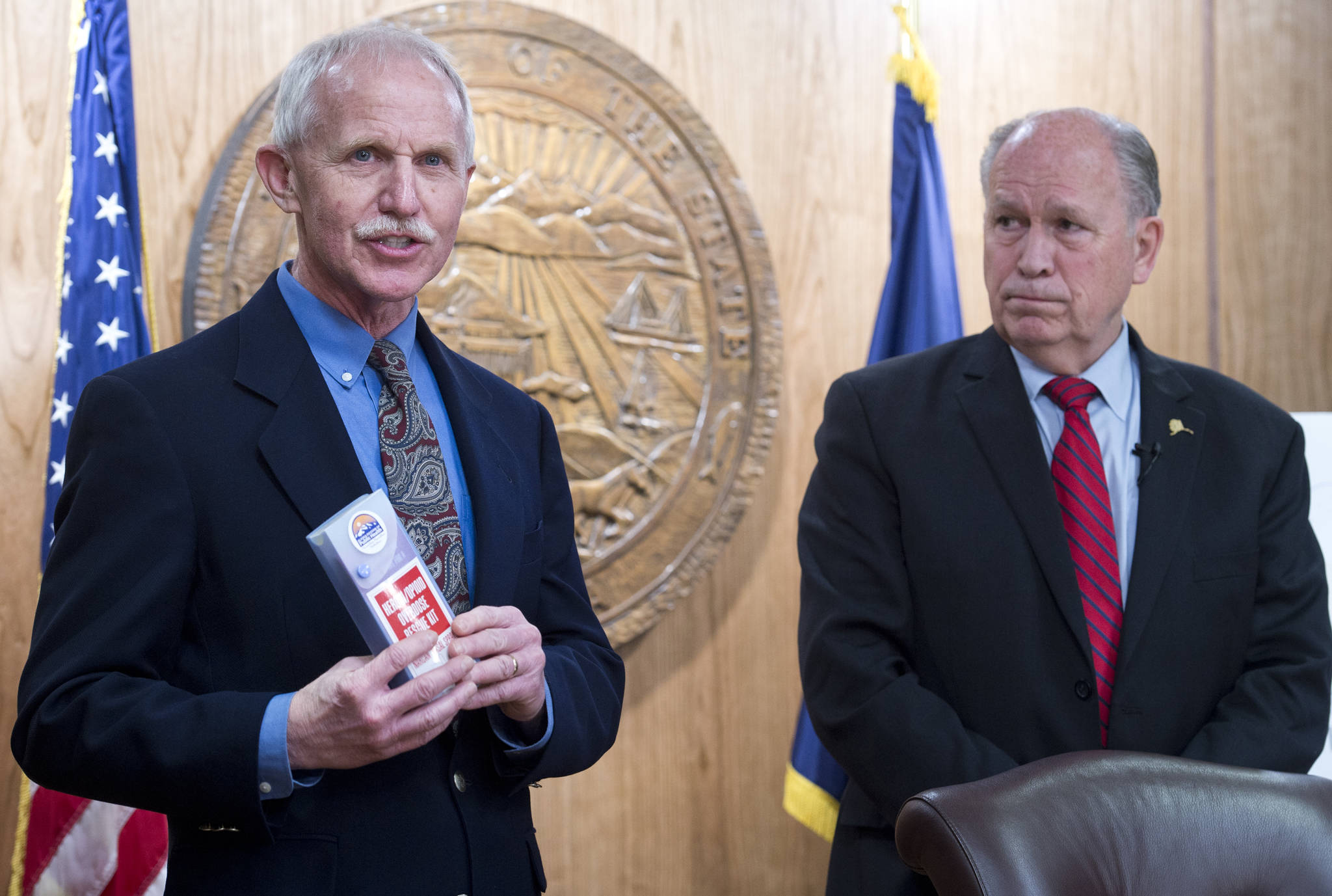 Dr. Jay Butler, Chief Medical Officer for the Department of Health and Social Services, left, speaks before Gov. Bill Walker signs SB 91 at the Capitol on Tuesday. The bill authorizes the chief medical officer of the DHSS to issue a standing order for the prescription of an opioid overdose drug. (Michael Penn | Juneau Empire)