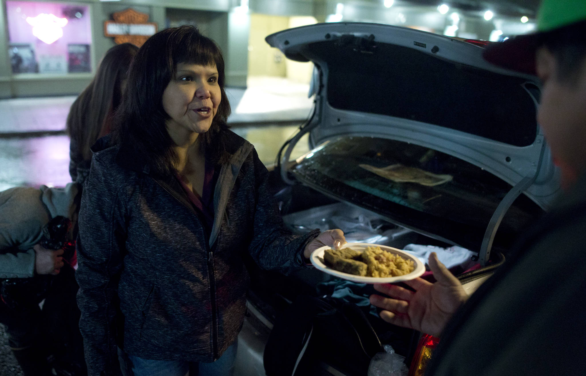 Roberta White serves hot food out of the back of a car to homeless people on South Franklin Street. (Michael Penn | Juneau Empire)
