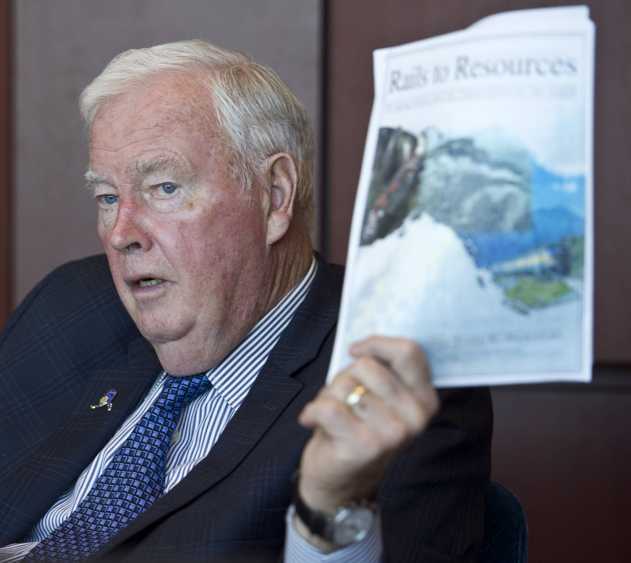 Former Alaska Gov. Frank Murkowski is traveling the state at the request of current Gov. Bill Walker to promote a railway connecting Alaska to Canadian rails. Murkowski is holding a Rails to Resources informational packet his office produced in June 2000 when he was a U.S. Senator for Alaska. (Michael Penn | Juneau Empire)