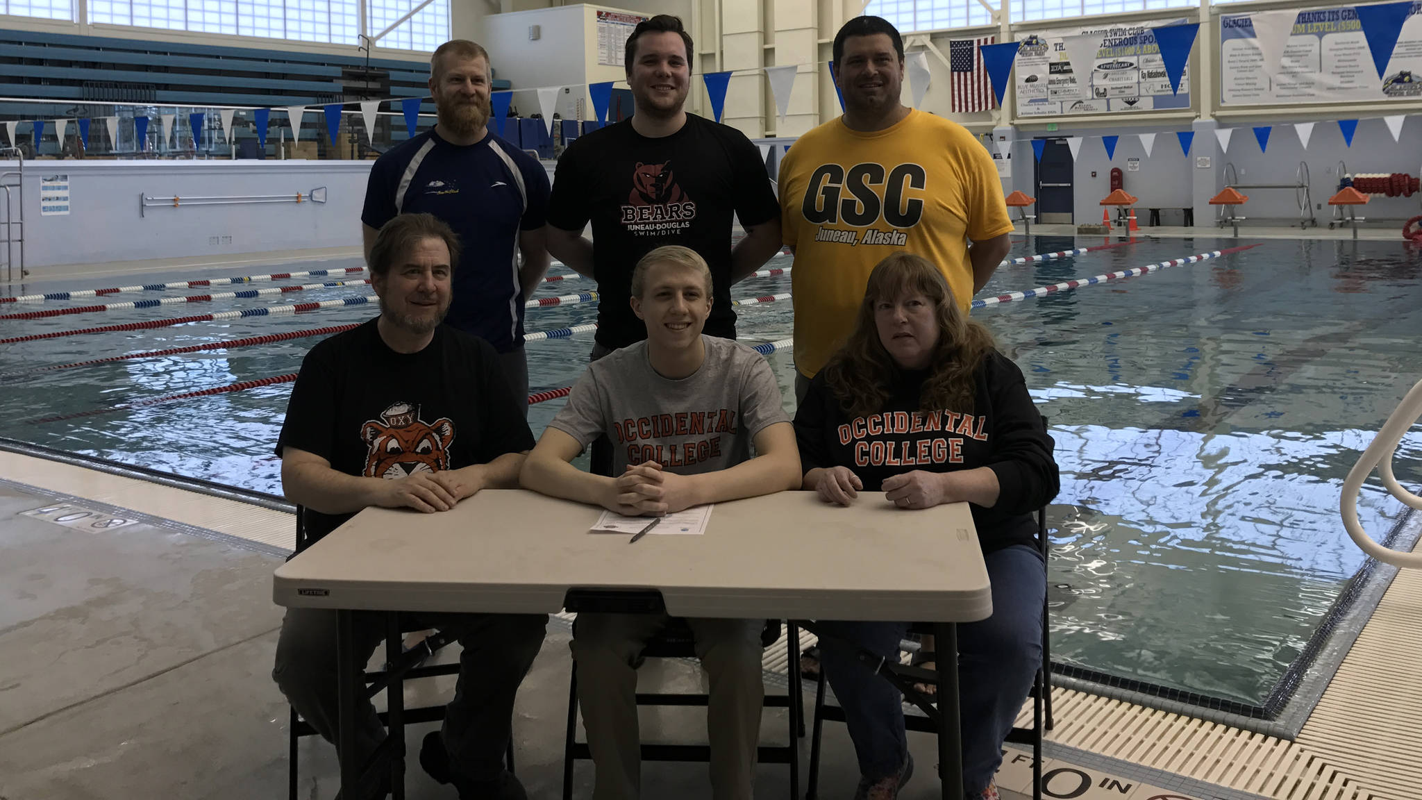 Aidan Seid, seated in the middle, poses with his parents, David and Carolyn, and Glacier Swim Club and high school swim coaches Scott Griffith, Seth Cayce and Robby Jarvil while signing a national letter of intent to swim at Occidental College, April 8, at the Dimond Park Aquatic Center. (Photo courtesy of Scott Griffith)