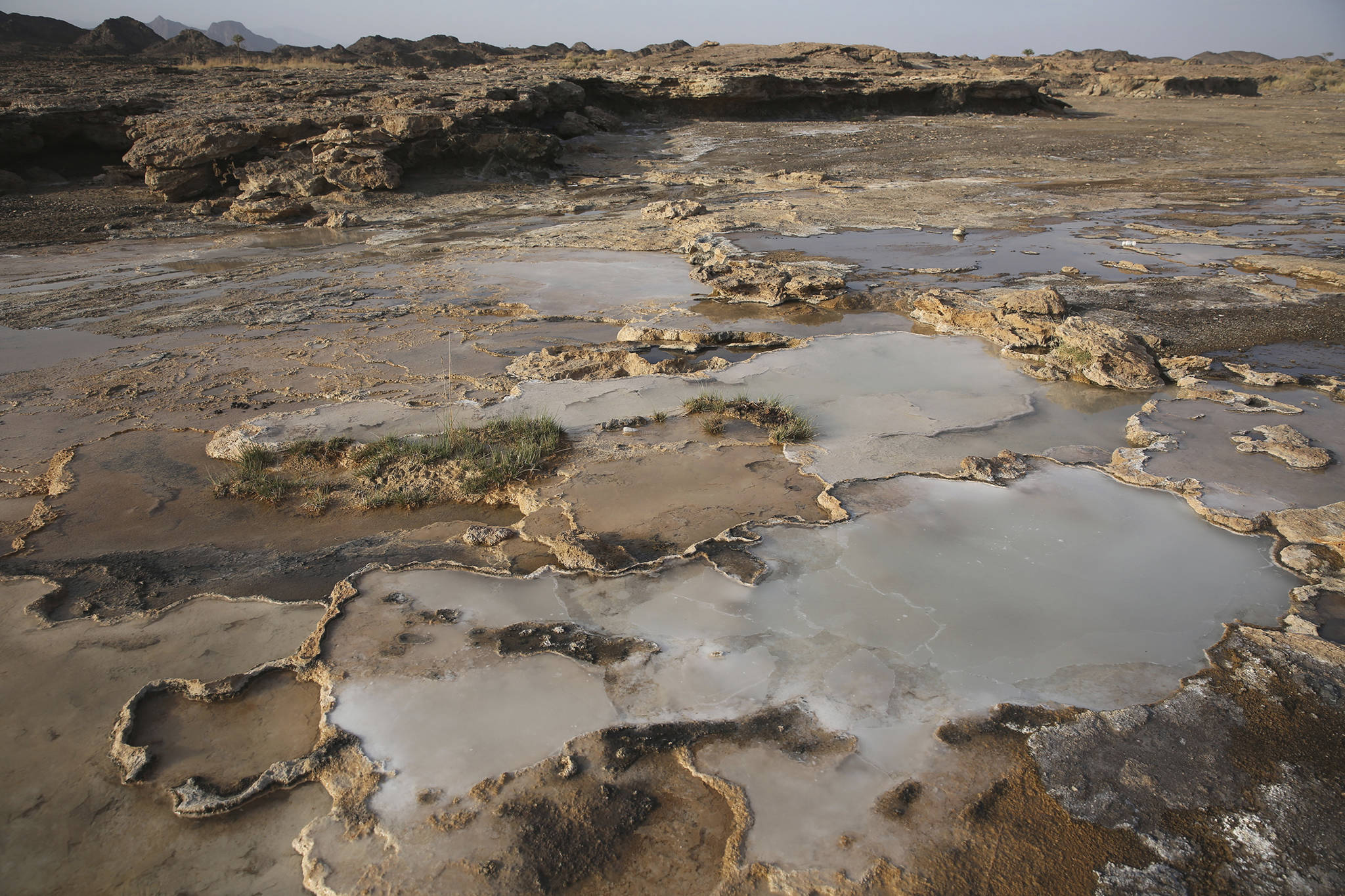 This March 5 photo shows travertine pools with white films of carbon fused with calcium, a chemical process being explored by a geological research project, in the al-Hajjar mountains of Oman. Deep in the jagged red mountains, geologists from the Oman Drilling Project are drilling in search of the holy grail of reversing climate change: an efficient and cheap way to remove carbon dioxide from the air and oceans. They are coring samples from one of the world’s only exposed sections of the Earth’s mantle to uncover how a spontaneous natural process millions of years ago transformed CO2 into limestone and marble. (Sam McNeil | The Associated Press)