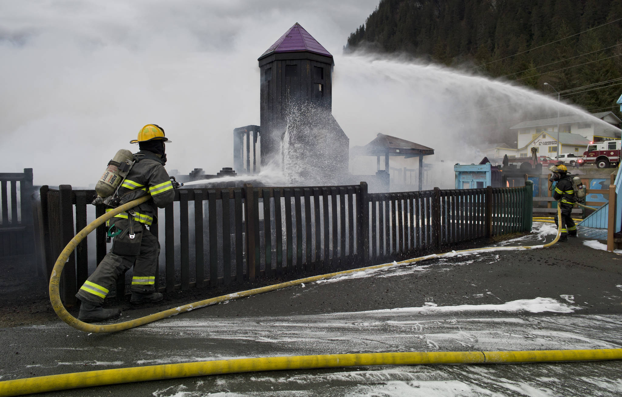 Capital City Fire/Rescue personnel fire a fire that consumes the playground at Twin Lakes on Monday, April 24, 2017. (Michael Penn | Juneau Empire)
