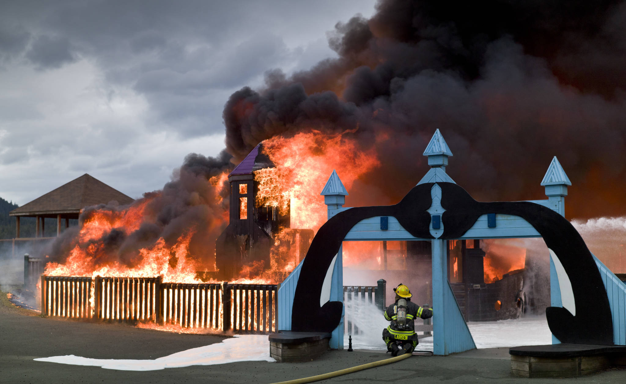 Capital City Fire/Rescue personnel fire a fire that consumes the playground at Twin Lakes on Monday, April 24, 2017. (Michael Penn | Juneau Empire)