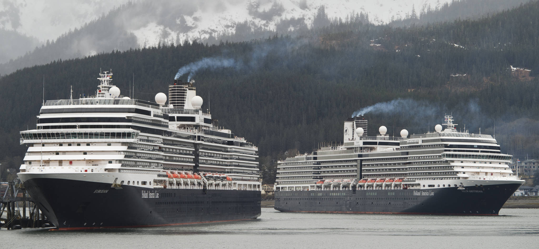 The Holland Amerca Line’s Nieuw Amsterdam, right, pulls into Juneau’s downtown harbor as sister ship Eurodam ties up at the AJ Dock on Monday, May 1, 2017. The two ships are the first in a cruise season that is predicted to bring over a million passengers to Juneau. (Michael Penn | Juneau Empire)