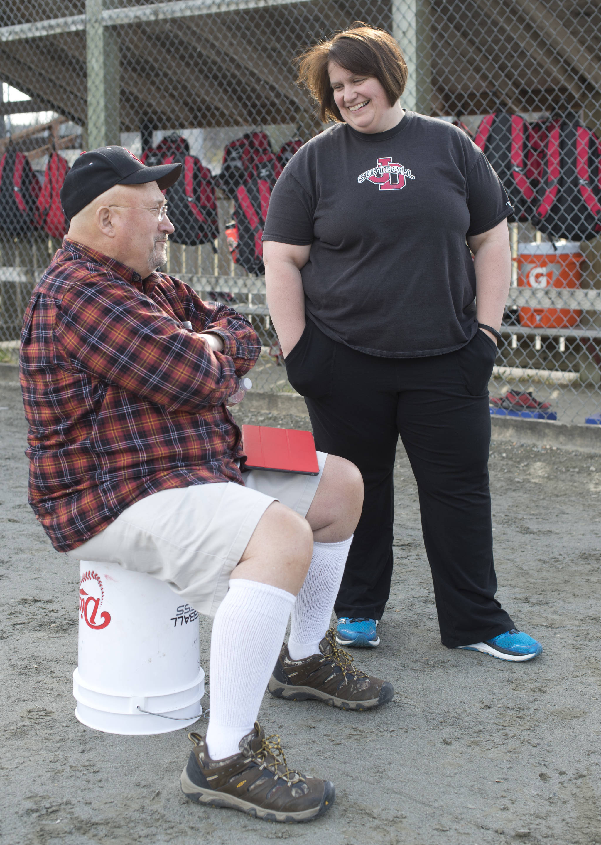 Juneau-Douglas High School girls varsity softball head coach Lexie Razor talks with former head coach Dave Massey during practice at Melvin Park on Tuesday, April 25, 2017. (Michael Penn | Juneau Empire)