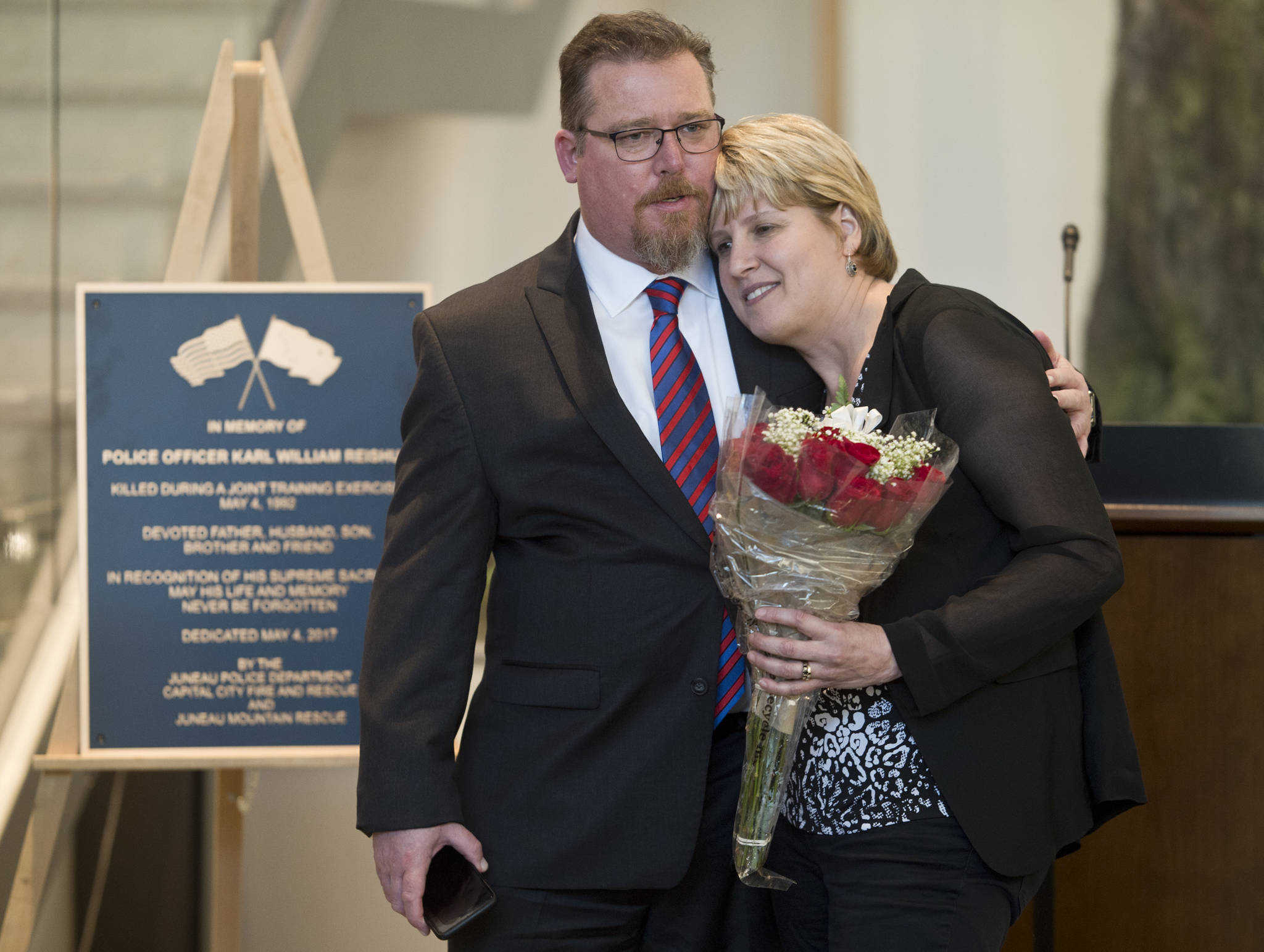 Former Juneau firefighter Dave Stott gives Sue Reishus-O’Brien a hug at a remembrance ceremony at the Father Andrew P. Kashevaroff Building on Thursday, May 4, 2017, on the 25th anniversary of the death of Sue’s then-husband, Police Officer Karl William Reishus. Stott was injured in the same training accident that killed Reishus. (Michael Penn | Juneau Empire)