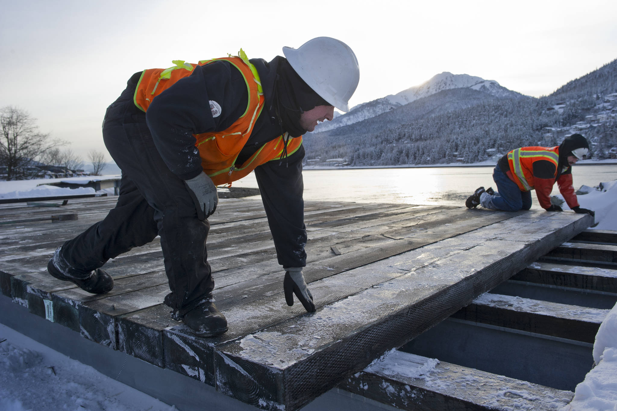 Mark Mitchell, left, and Spencer Davis, of North Pacific Erectors, align some of the last planks to be laid on the newest Sea Walk near the Bridge Park on Thursday, Dec. 8, 2016. (Michael Penn | Juneau Empire File)