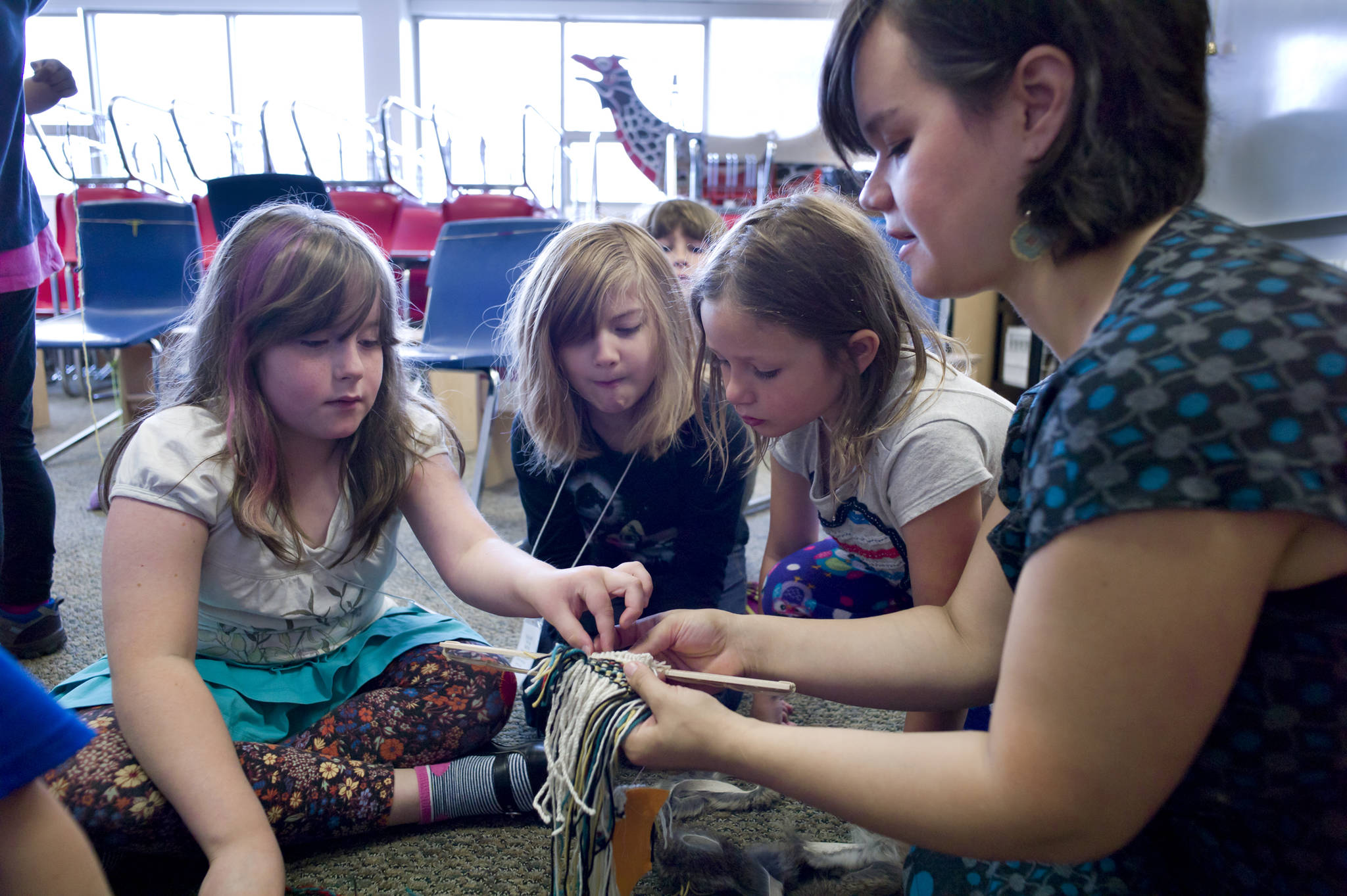 In this file photo from June 2015, instructor Lily Hope helps Maisy Messing, left, with ravenstail weaving as Sofia Lindoff, center, and Zoie Branch watch during their Juneau Fine Arts Camp class at Juneau-Douglas High School. (Michael Penn | Juneau Empire File)
