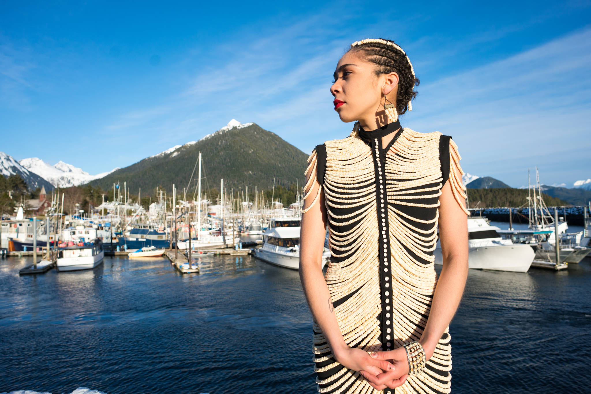 Mia Nevarez stands in front of Crescent Harbor in Sitka wearing a salmon dress that Cynthia Gibson made from 20,000 salmon vertebrae. (Photo by Bethany Goodrich)