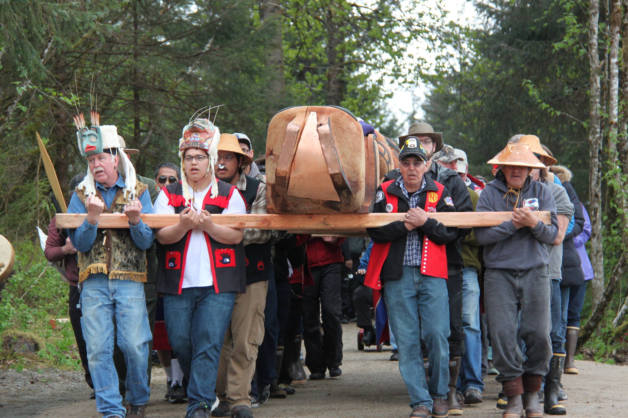 Tribal members carry the Raven Totem Pole to its site flanking the Huna Tribal House. (Mary Beth Moss | For the Capital City Weekly)