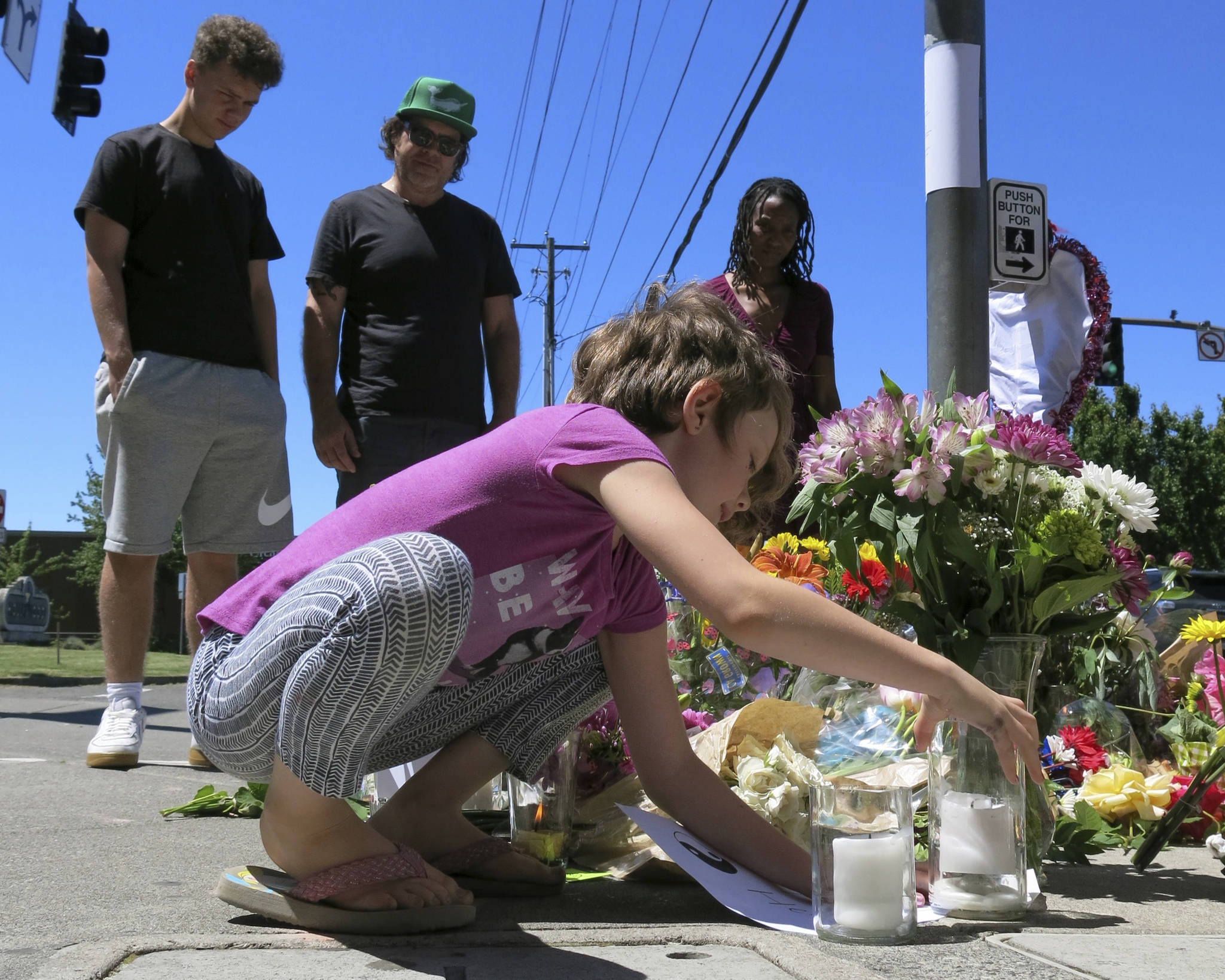 Coco Douglas, 8, leaves a handmade sign and rocks she painted at a memorial in Portland, Oregon on Saturday, May 27, 2017, for two bystanders who were stabbed to death Friday while trying to stop a man who was yelling anti-Muslim slurs and acting aggressively toward two young women. From left are Coco’s brother, Desmond Douglas; her father, Christopher Douglas; and her stepmother, Angel Sauls. (Gillian Flaccus | The Associated Press)