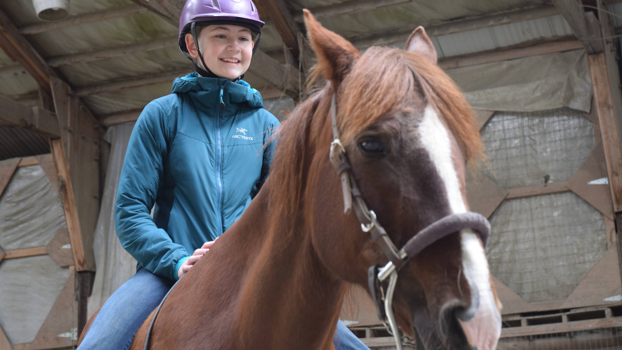 Kate Debuse, 14, smiles as she takes a break in riding her horse Sweetie in the Fairweather Barn, Tuesday, June 7. (Nolin Ainsworth | Juneau Empire)