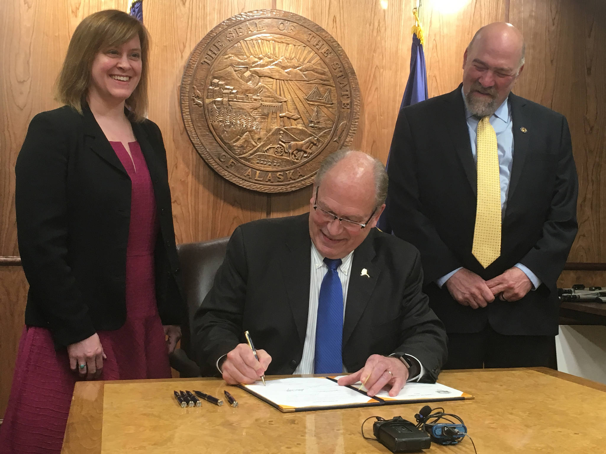 James Brooks | Juneau Empire Sen. Mia Costello, R-Anchorage, and Rep. Adam Wool, D-Fairbanks, smile as Gov. Bill Walker signs House Bill 132, which allows ride-sharing companies to operate in Alaska, on Thursday in the Capitol.