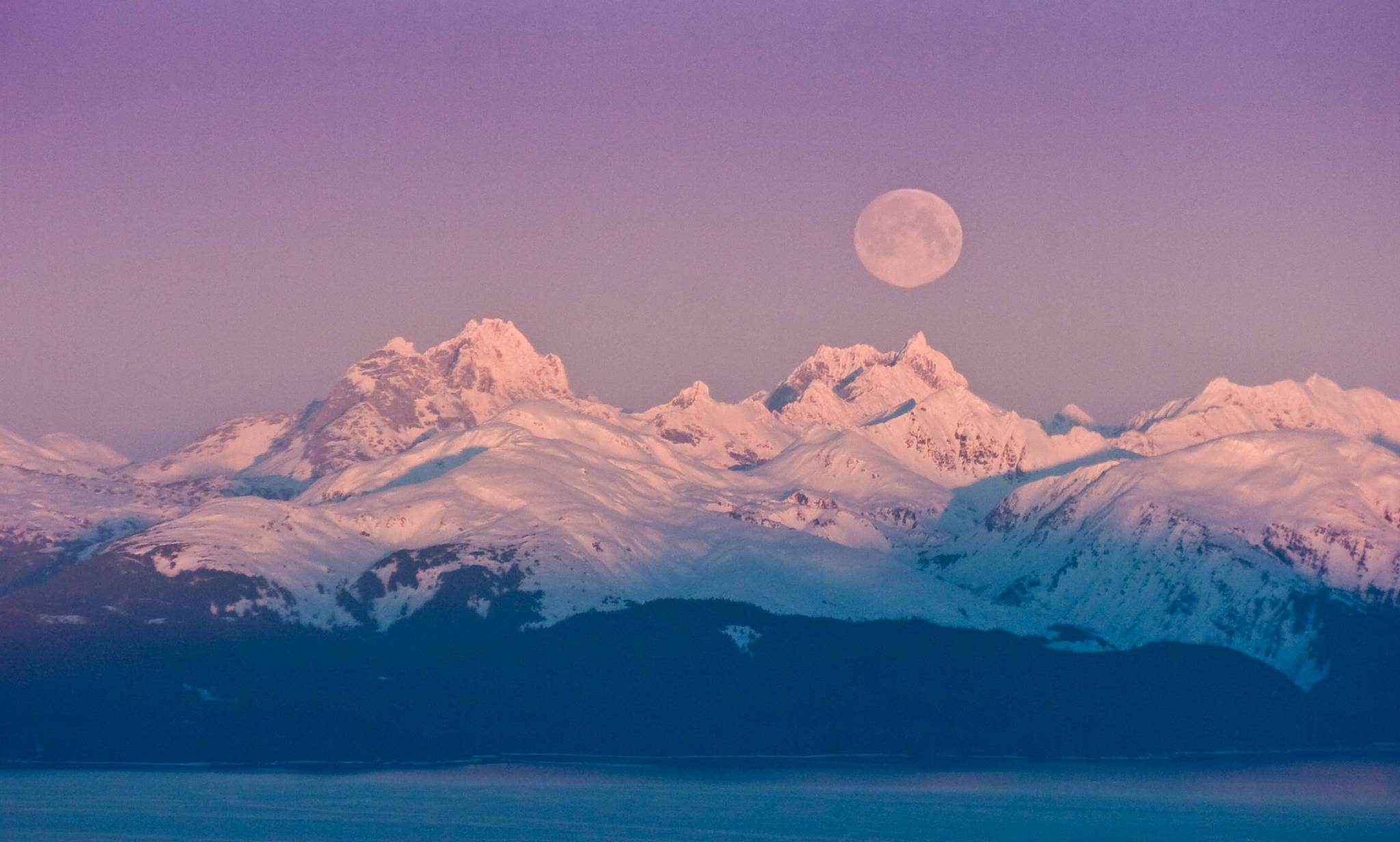 A full moon sets over the Chilkat Mountain Range on the west side of Lynn Canal. (Michael Penn | Juneau Empire file)