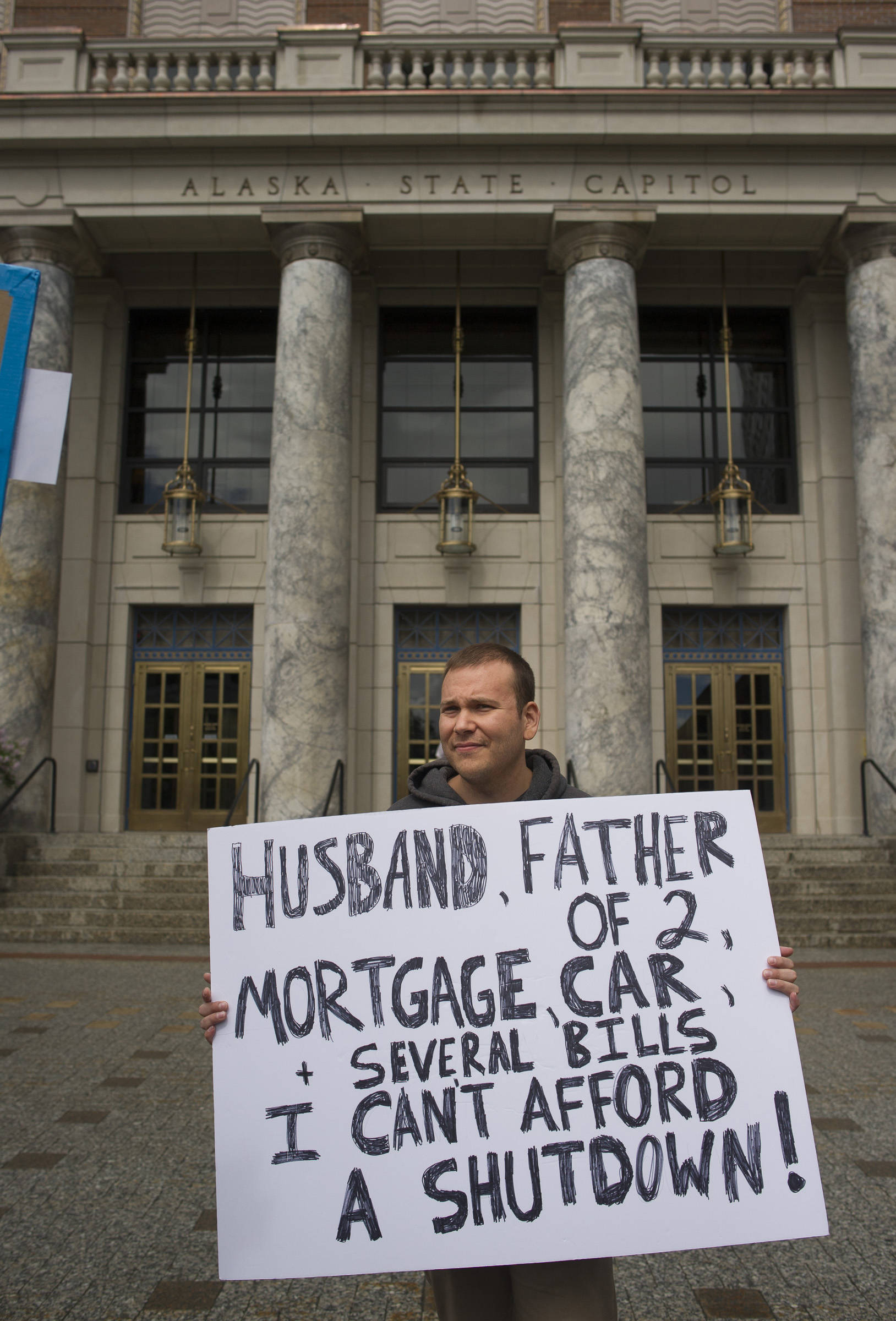 Bradley Johnson, a state employee at the Department of Revenue, holds his protest sign during noon rally against the Legislature’s lack of a budget compromise on Thursday, June 22, 2017. (Michael Penn | Juneau Empire)