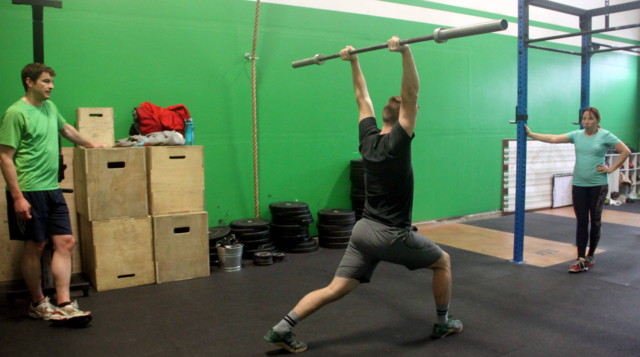 Max Rice, an instructor at Tongass Crossfit, demonstrates proper lifting posture for his students before starting them on their own round of power lifting exercises. (Erin Granger | Juneau Empire)