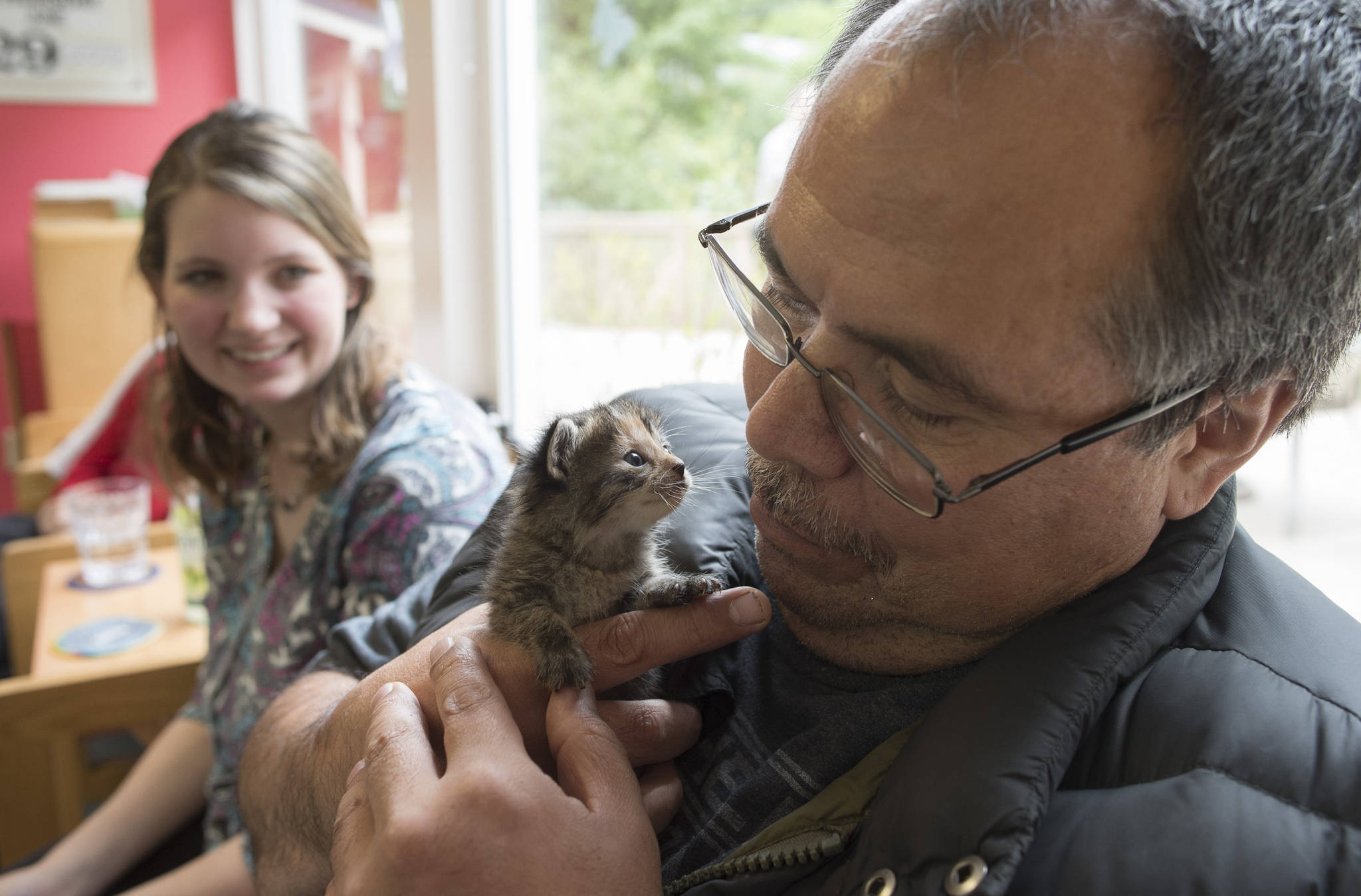 Don Eames gets a visit from a 4-week-old kitten as Bridge Adult Day Program supervisor Kelsey Wood watches on Thursday, June 29, 2017. Animals from the Gastineau Humane Society are brought to the program for an hour long visit every month. (Michael Penn | Juneau Empire)