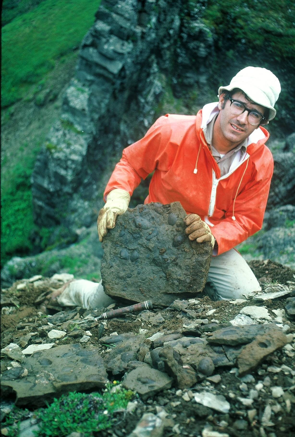 A slab of sandstone with 10-million-year-old shells; tired at the end of a long day at Cape Tachilni, by Cold Bay, Alaska, 1977. Photo courtesy of Lou Marincovich.