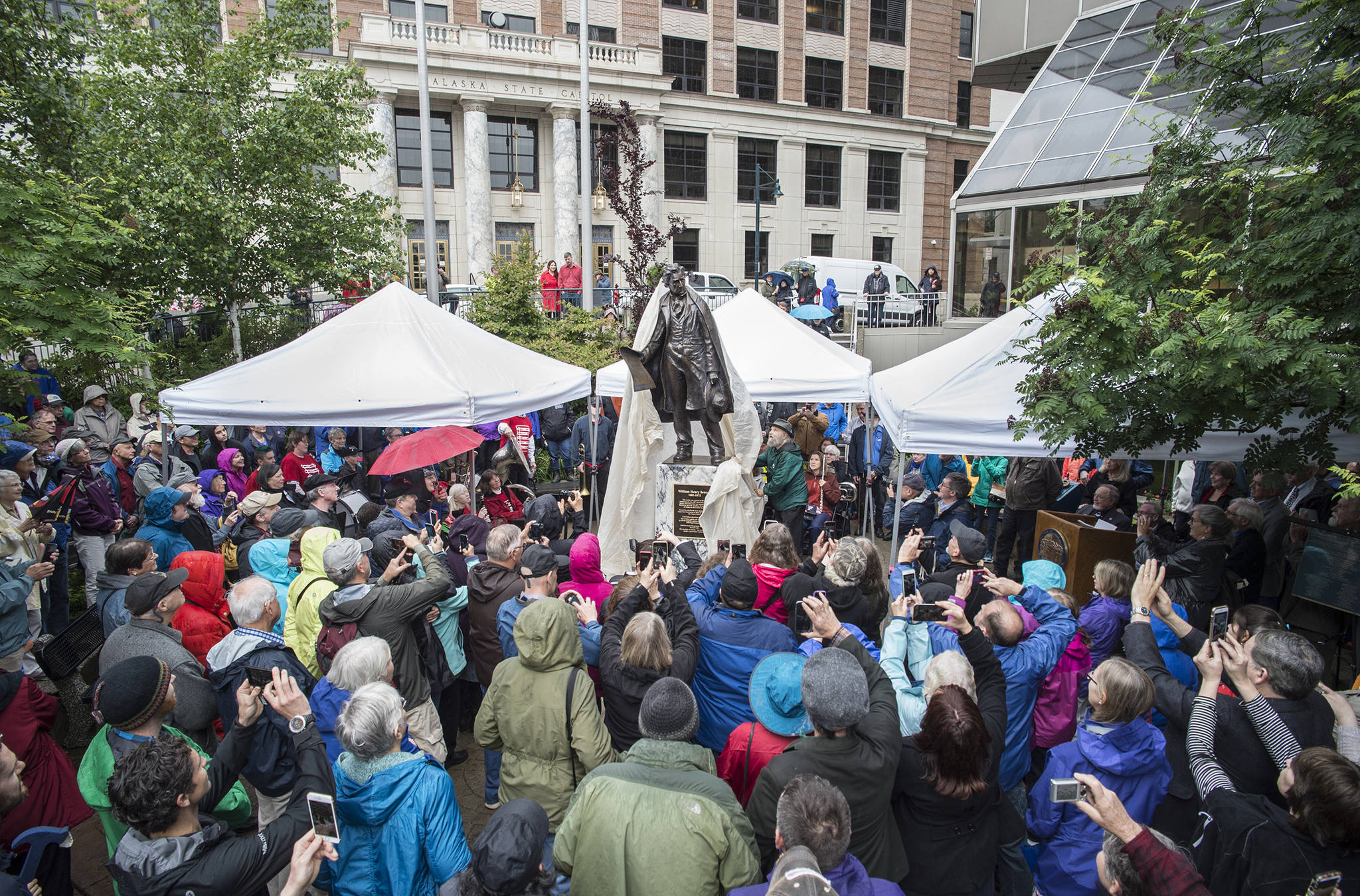 Dave Rubin, of Ketchikan, pulls the veil off the bronze statue of William Seward he designed and made with his sister, Judy, during a ceremony in the Dimond Courthouse Plaza on Monday, July 3, 2017. (Michael Penn | Juneau Empire)