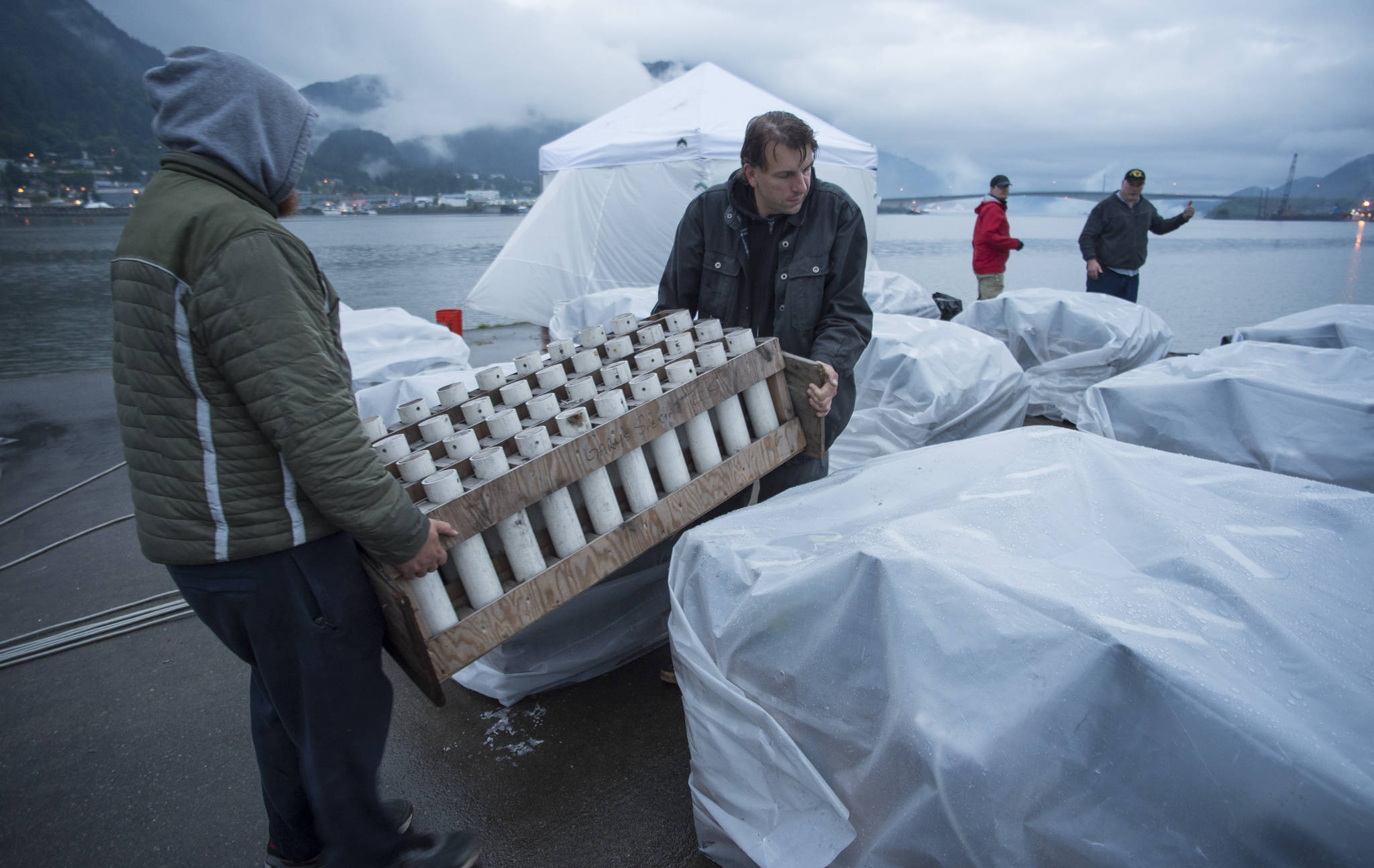 Volunteers Sam Cartmill, left, and Ian Dinneford carry rocket launchers into place before the annual city-funded fireworks show in Juneau’s downtown harbor on Tuesday, July 3, 2017. (Michael Penn | Juneau Empire)