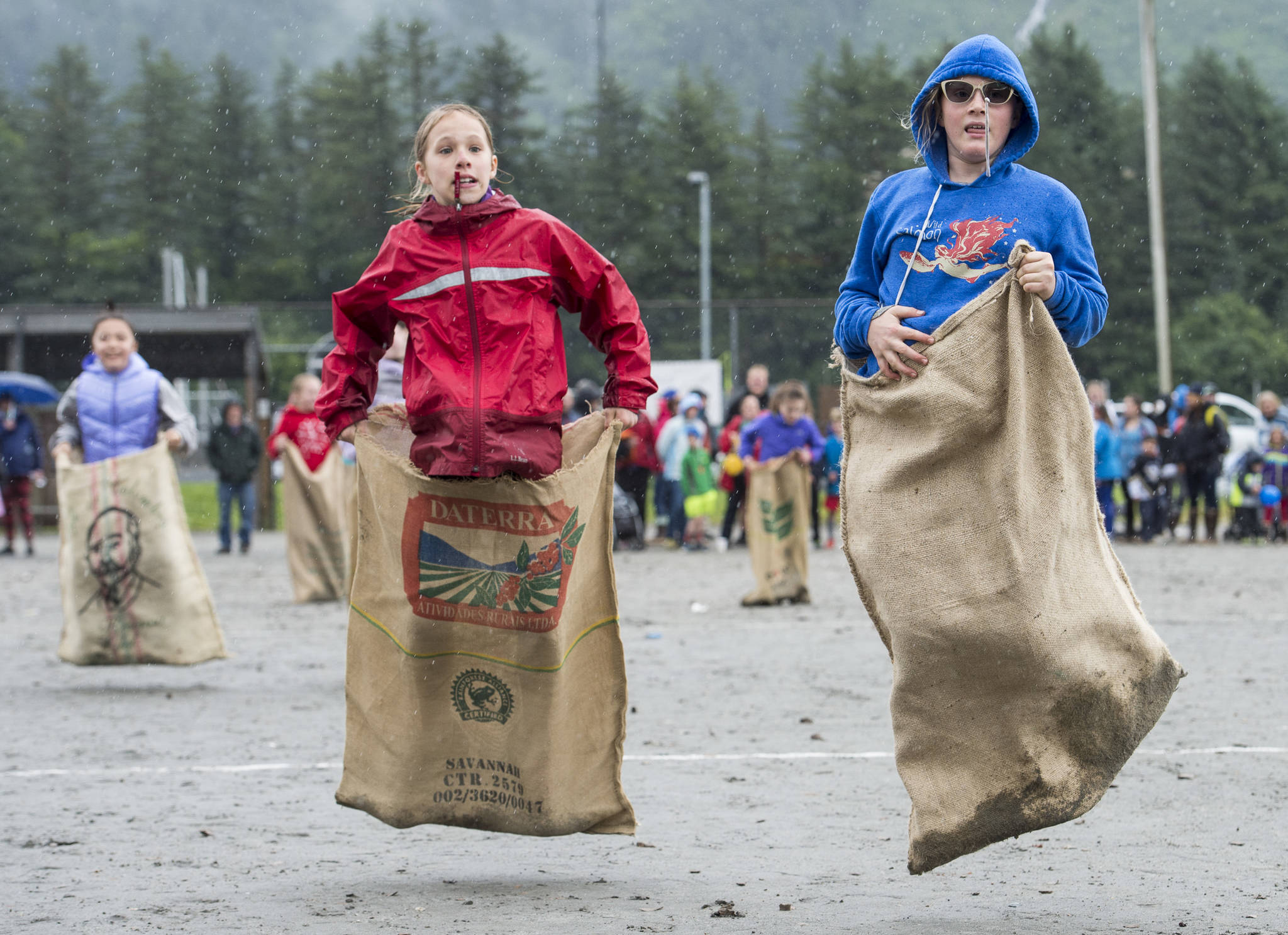 Molly McCauley, 10, right, beats Harper Wilkens, 10, by a leap in the gunny sack race during the 4th of July activities in Douglas on Tuesday, July 4, 2017. (Michael Penn | Juneau Empire)