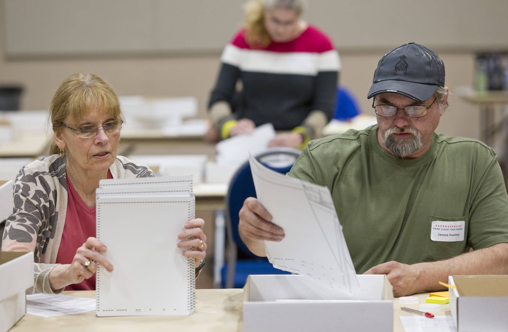 In this August 2016 photo, hand count team members Christine Niemi, left, and James Fowlkes count ballots at Centennial Hall from the state-wide primary election. (Michael Penn | Juneau Empire File)