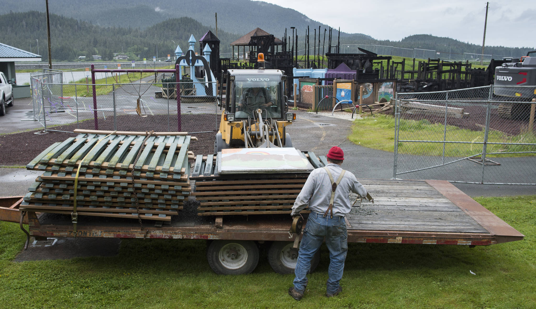 Sections of picket fence are loaded onto a flatbed trailer as work begins on the demolition of Project Playground at Twin Lakes on Tuesday, June 20, 2017. Recent tests revealed that soil at the site is not contaminated, and the city will be planting grass at the site soon. (Michael Penn | Juneau Empire)