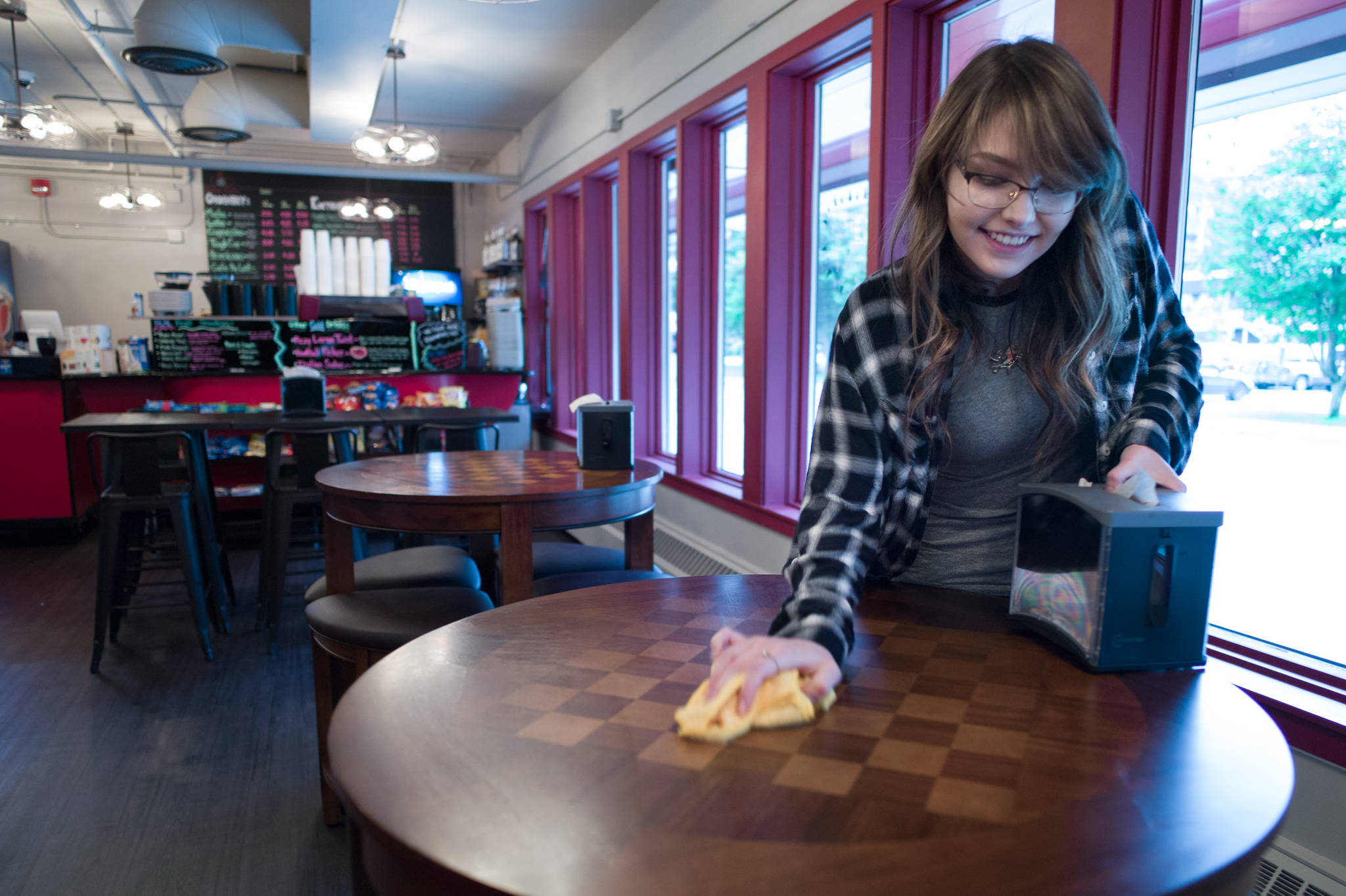 Alison Schoonover cleans up after the noon rush at a new coffee shop called Sacred Grounds located inside the Andrew Hope Building on Tuesday, July 18, 2017. (Michael Penn | Juneau Empire)