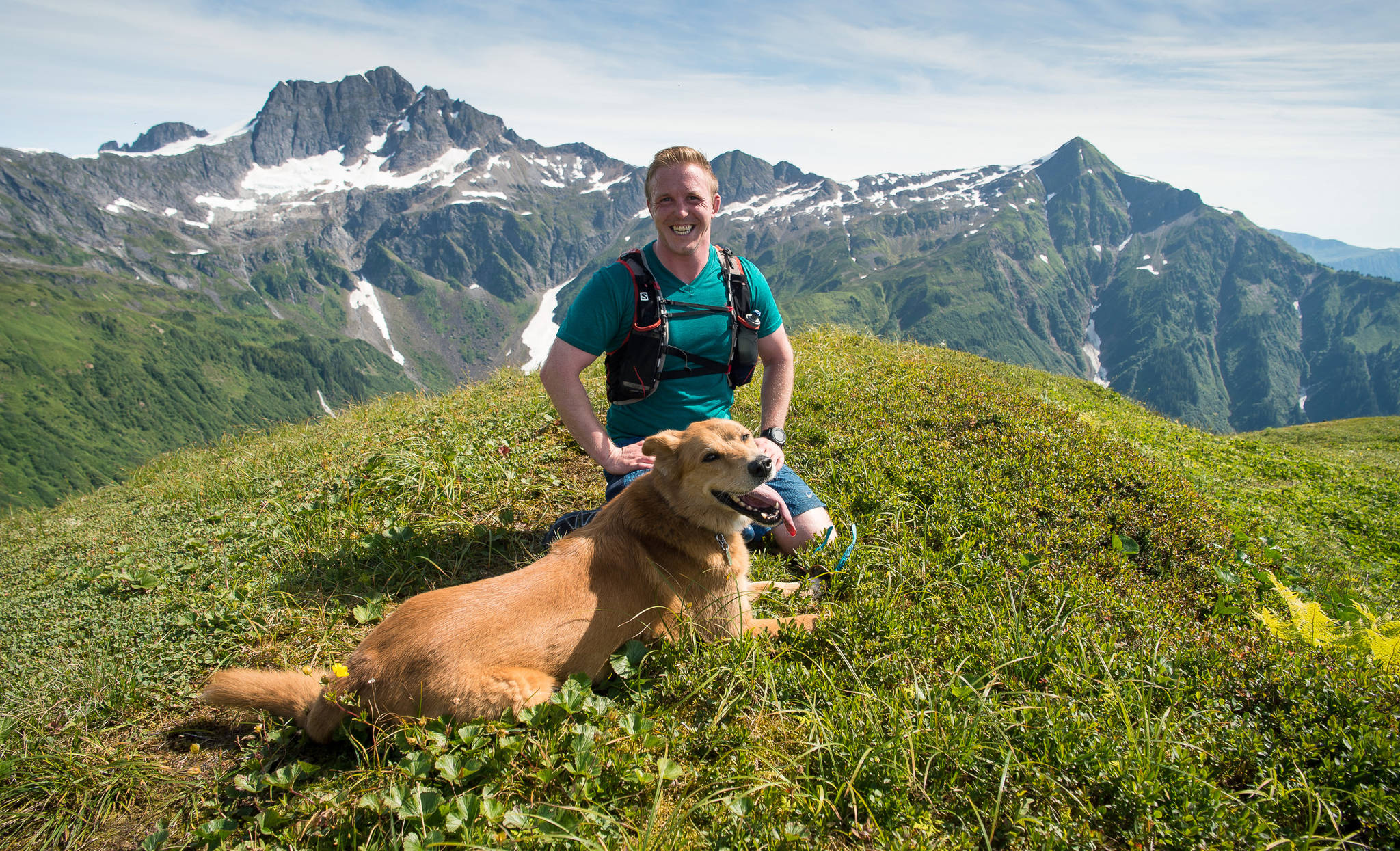Against a backdrop of Stoller White Mountain, left, and Mount McGinnis, ultramarathon runner Houston Laws poses with Sadie during a run up Grandchild Peak on Thursday, August 10, 2017. (Michael Penn | Juneau Empire)