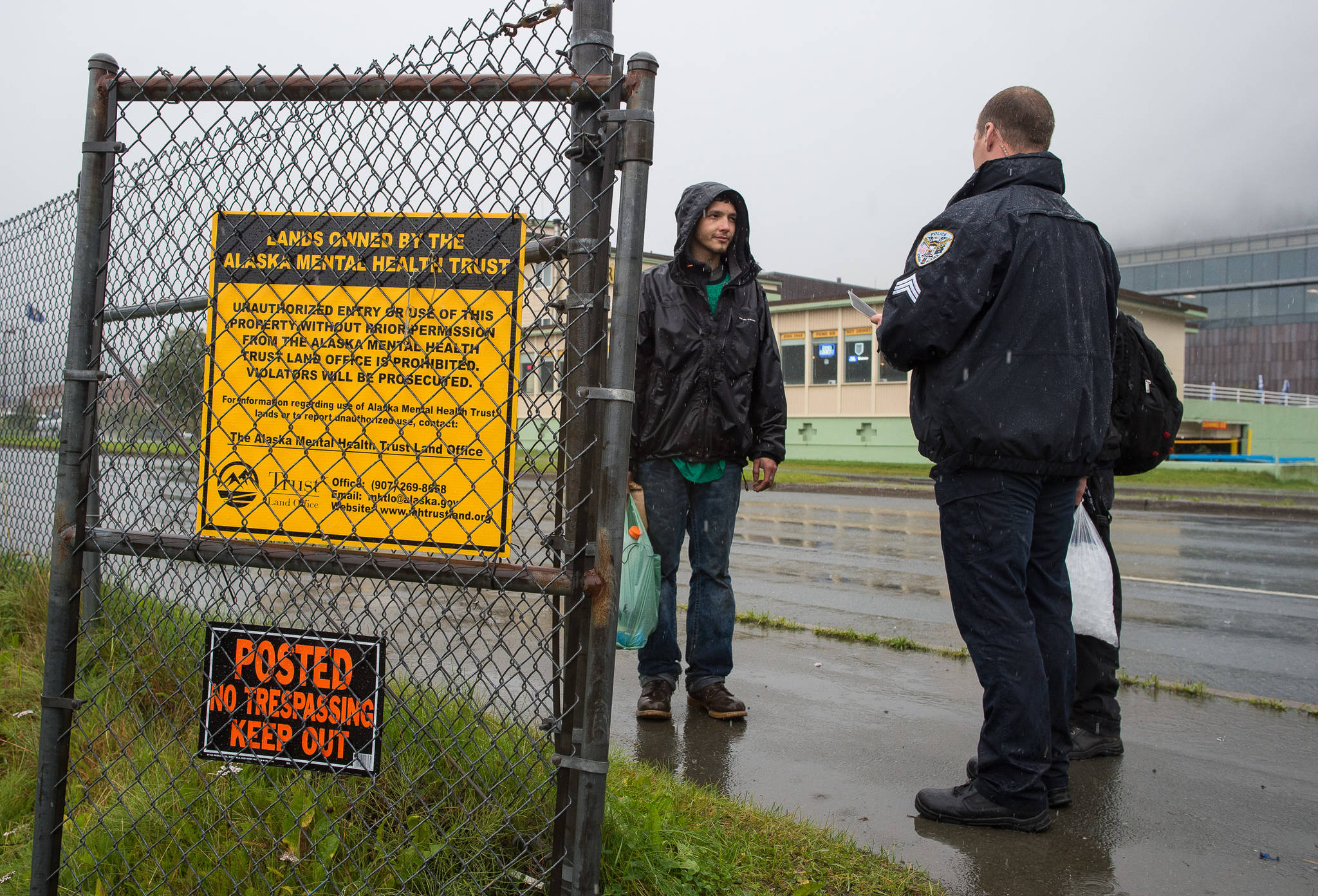 Juneau Police Department Officers serve eviction notices on homeless encampments as Alaska Mental Health Trust Authority employees look on on Tuesday, Aug. 22, 2017. (Michael Penn | Juneau Empire)