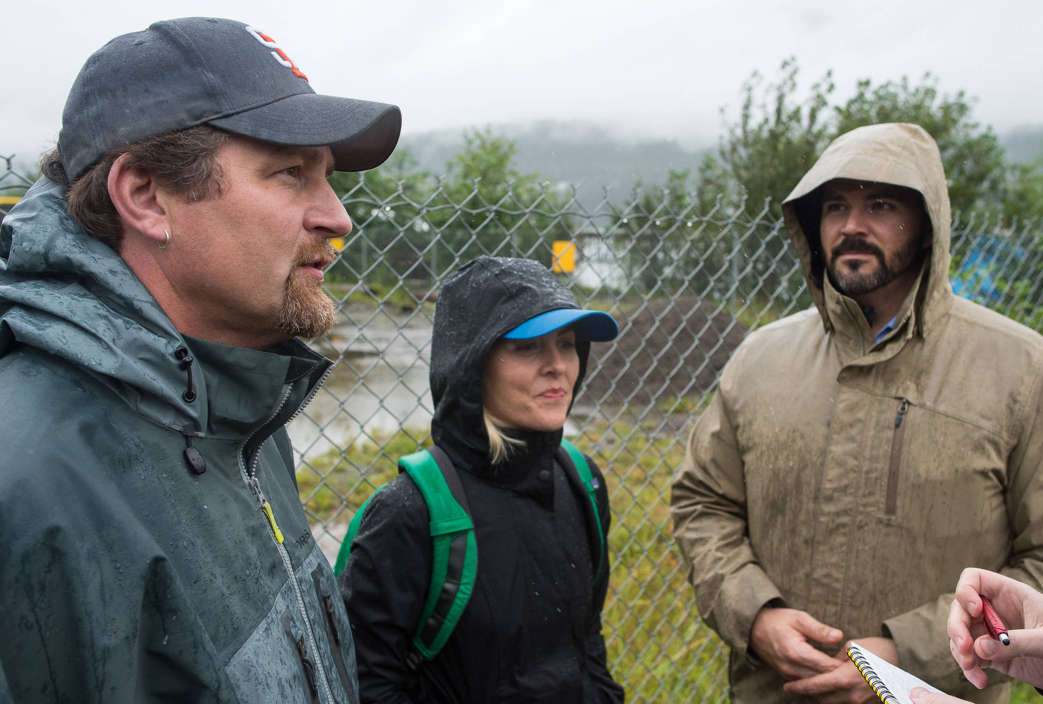 Alaska Mental Health Trust Authority Chief Operating Officer Steve Williams, left, Chief Communications Officer Carley Lawrence, center, and Executive Director John Morrison watch as Juneau Police Department Officers serve eviction notices on homeless encampments on Tuesday, Aug. 22, 2017. (Michael Penn | Juneau Empire)