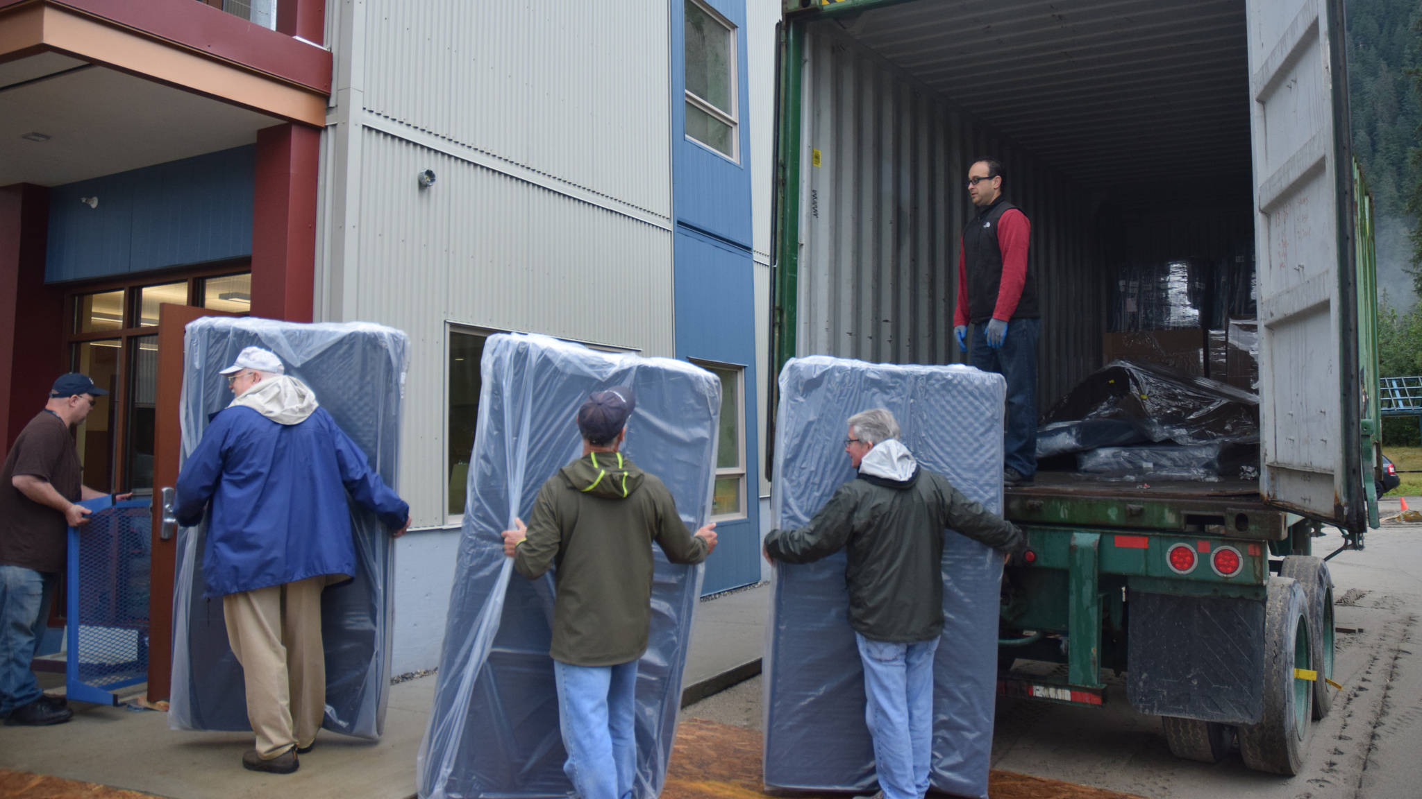 Rotary Club volunteers unload twin mattresses outside the Juneau Housing First studio apartments in Lemon Creek, Saturday, Aug. 26, 2017. (Kevin Gullufsen | Juneau Empire)