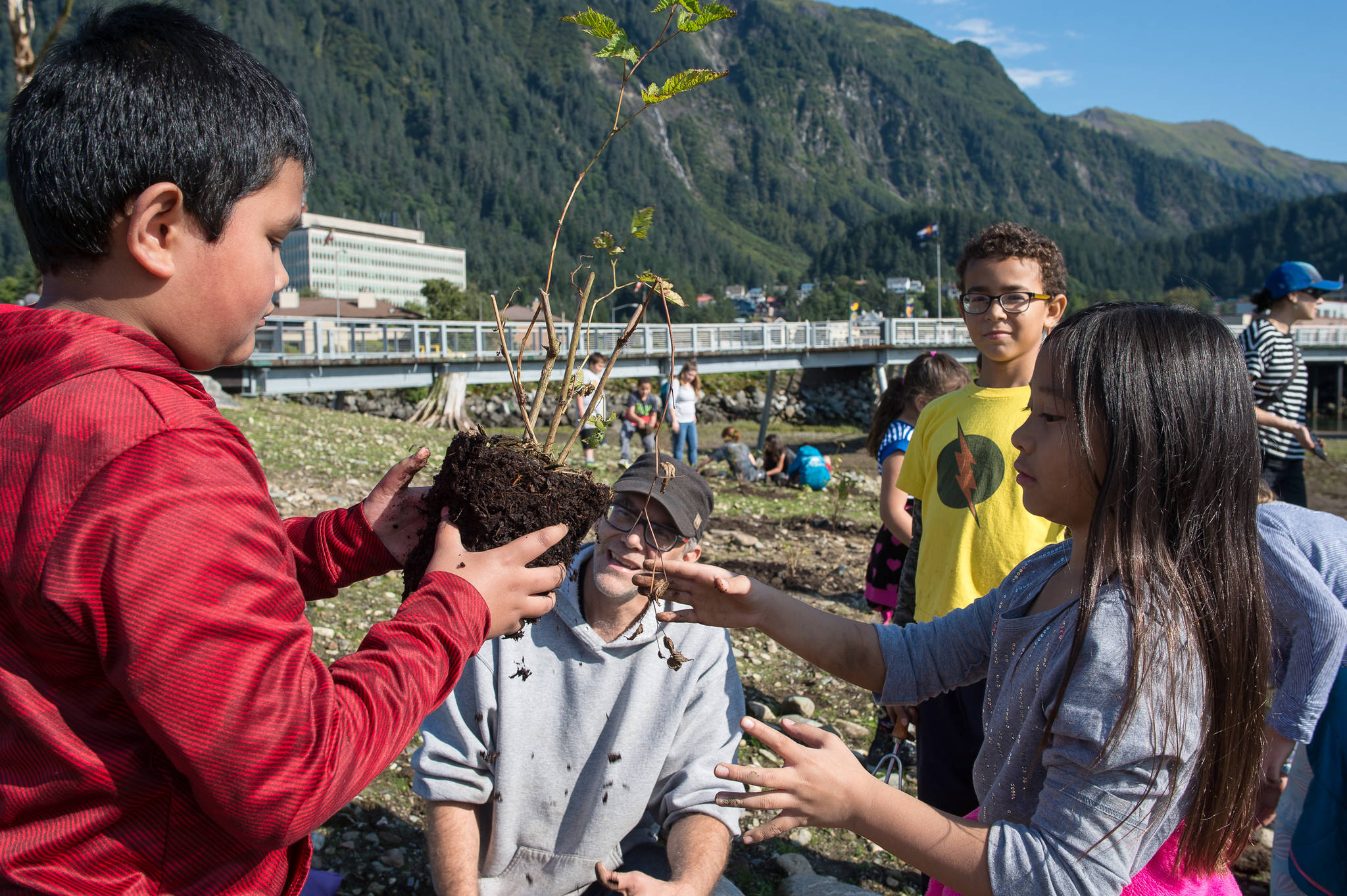 Ben Patterson, the city’s landscape maintenance supervisor, watches as fourth-grade students Jamal Canon, left, and Emery Marte from Harborview Elementary School plant salmonberries on a newly created island next to the Seawalk on Tuesday, Sept. 5, 2017. Harborview students will get a chance to plant 300 native species on the island over the next week to transform the area into habitat for birds. (Michael Penn | Juneau Empire)
