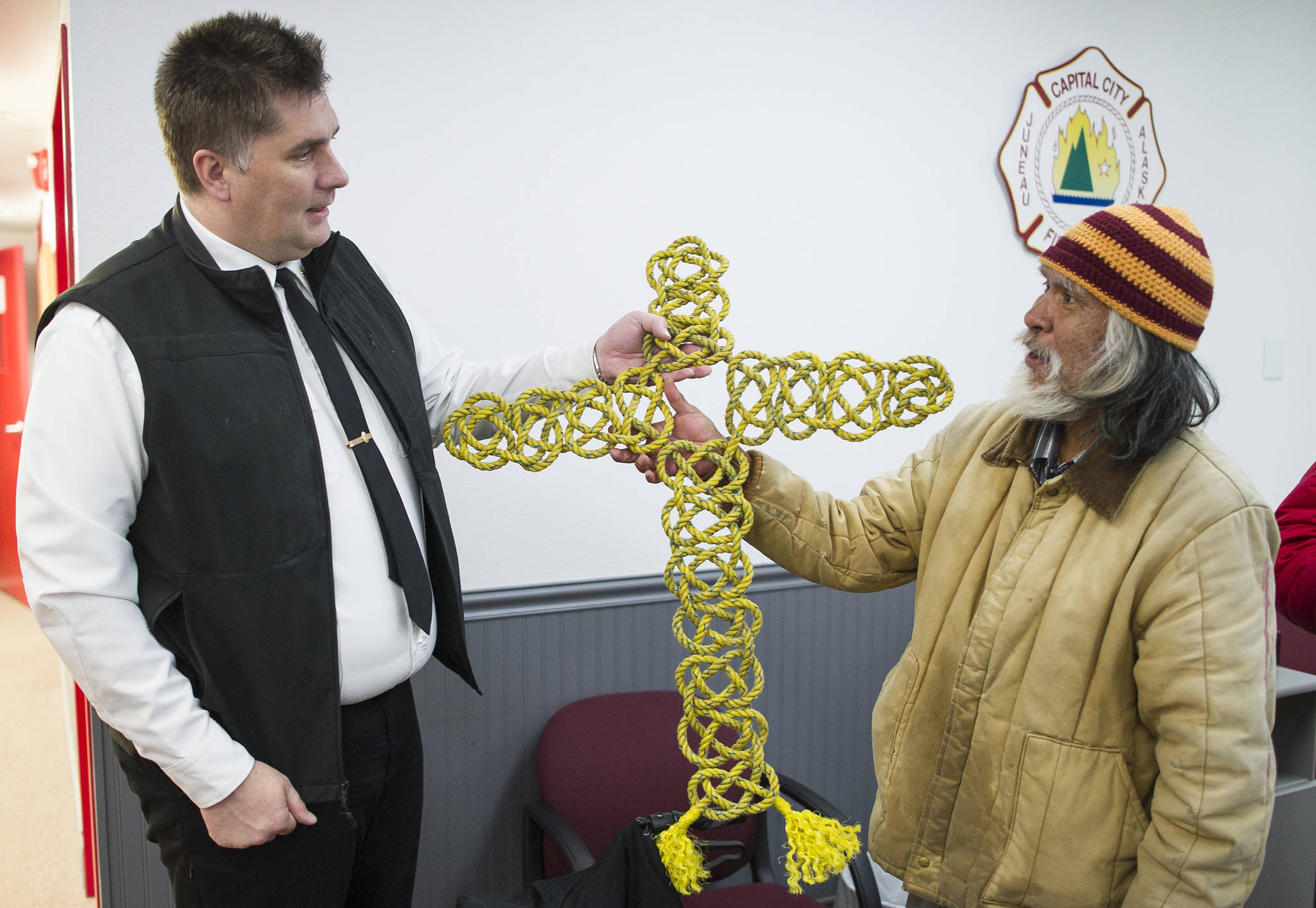 Thomas Bell, right, gives a woven-rope cross to Capital City Fire/Rescue Fire Chief Richard Etheridge in goodwill at the Downtown Fire Station on Monday, Sept. 11, 2017. Bell weaves the ropes previously used on crab pots to raise money but was looking to show his appreciation to the department for its work with the homeless. Bell is homeless and currently stays at the Glory Hole. (Michael Penn | Juneau Empire)