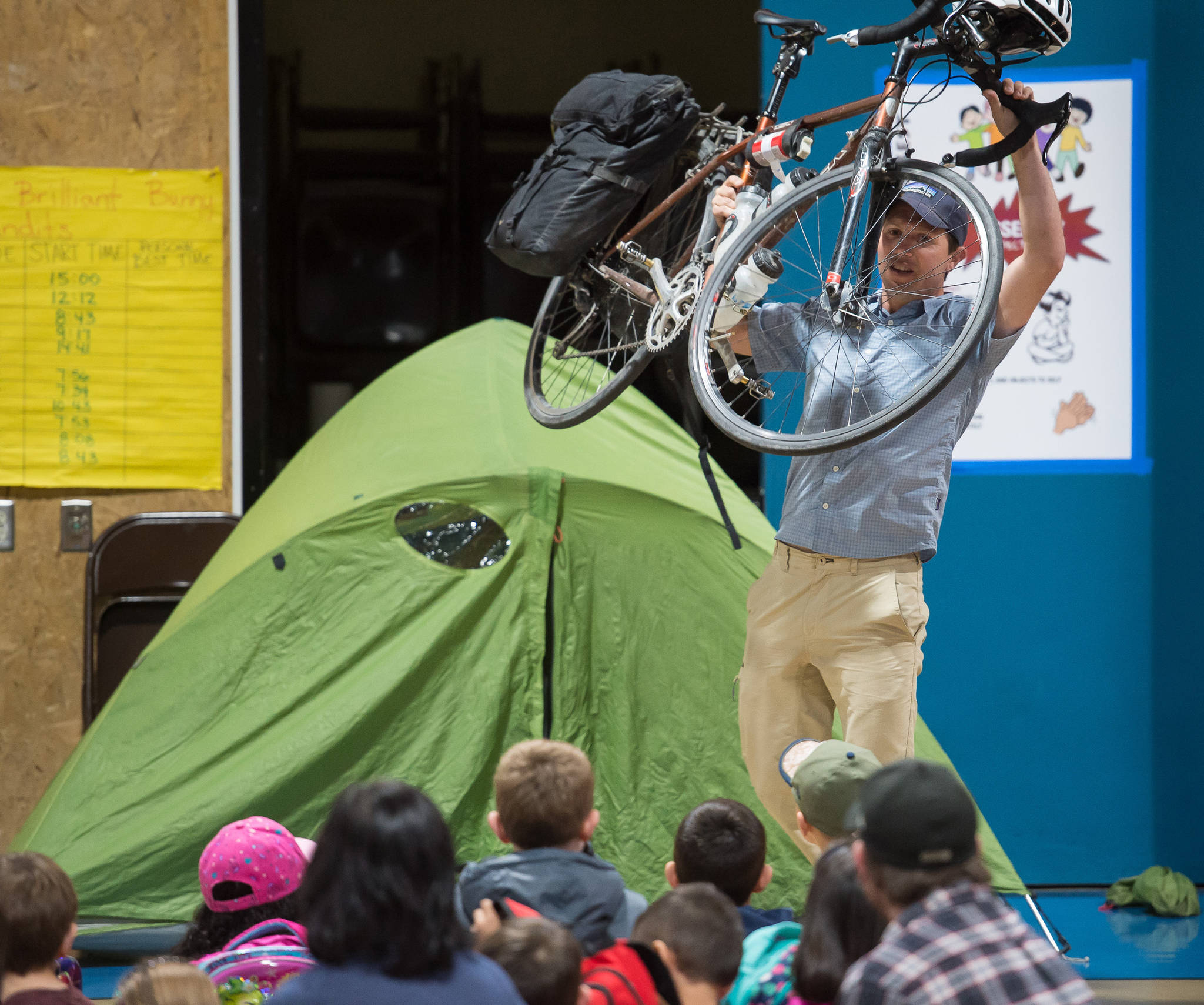 Chris Figureida shows off his touring bicycle and lightweight camping gear during a school assembly at Mendenhall River Community School on Friday, Sept. 15, 2017. (Michael Penn | Juneau Empire)