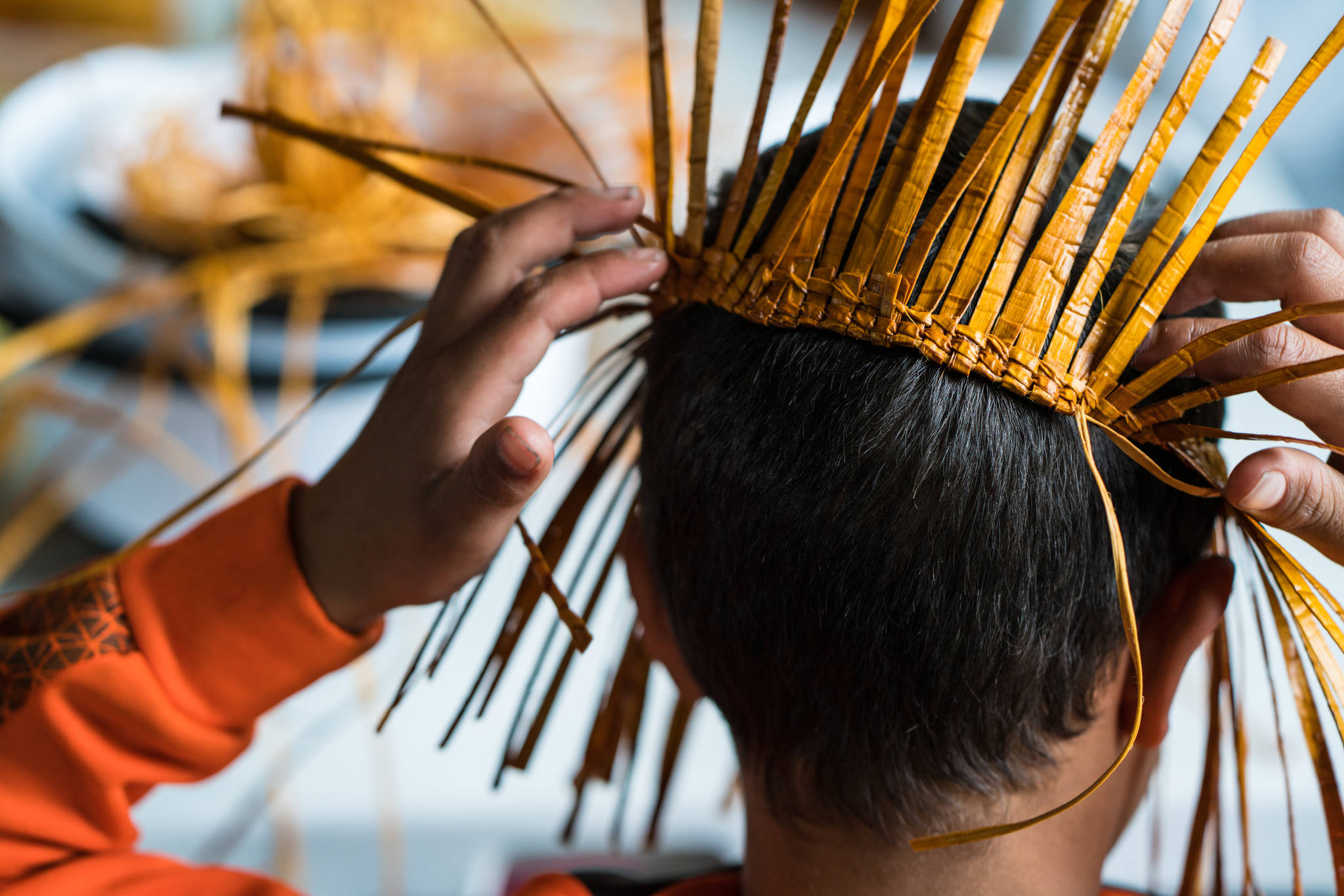 A camper excitedly tries the beginnings of a cedar hat on while learning to weave. (Photo by Bethany Goodrich)