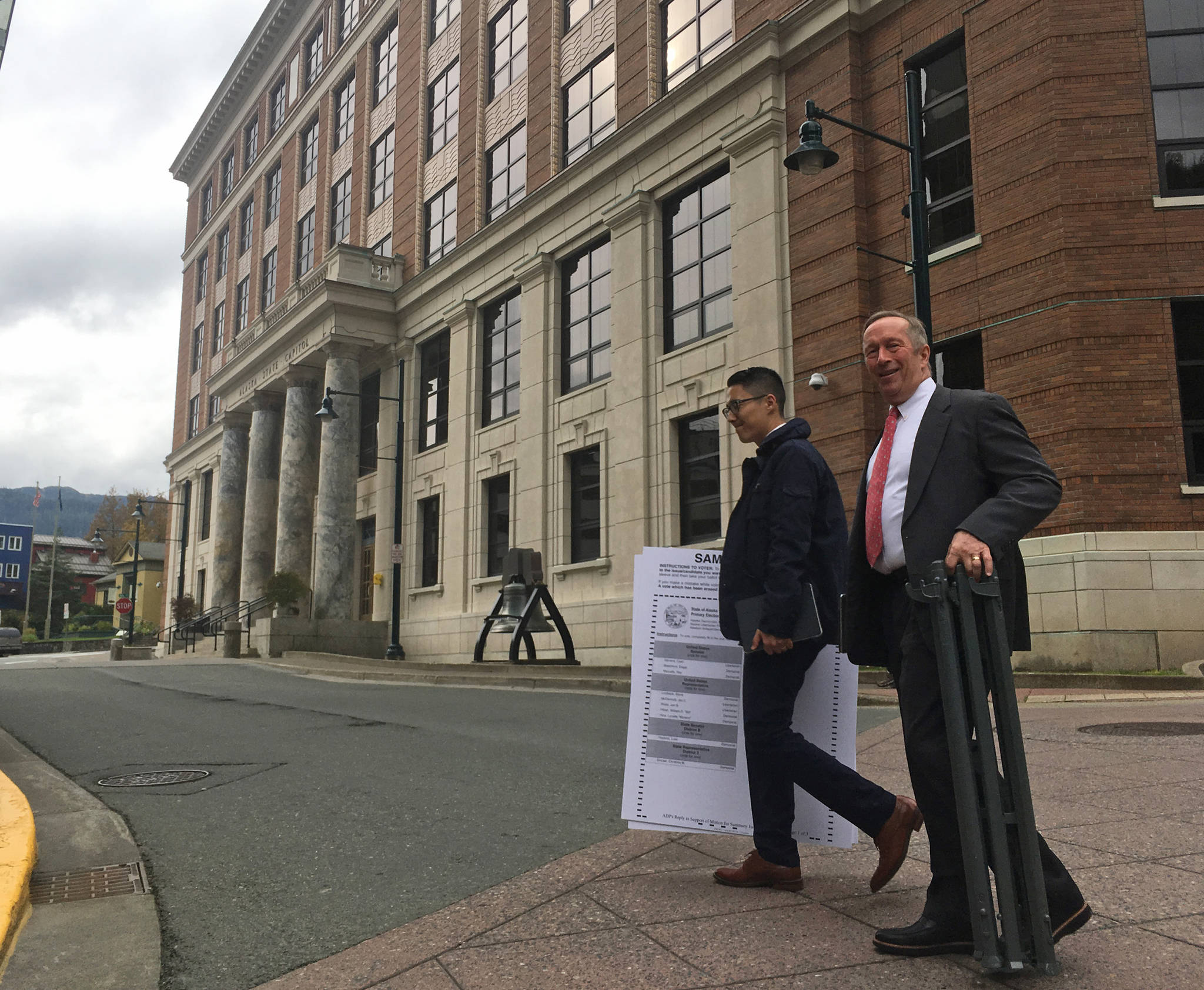 Attorneys Jon Choate, left, and Mark Choate, right, cross 4th Street on Thursday, Sept. 21, 2017. The two men were carrying exhibits to be used in their lawsuit against the state of Alaska on behalf of the Alaska Democratic Party. At background is the Alaska State Capitol. (James Brooks | Juneau Empire)