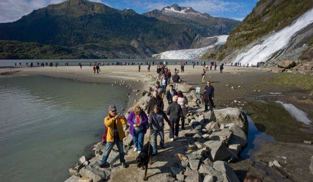 In this 2014 photo, visitors to the Mendenhall Glacier Recreation Area walk to and from Nugget Falls in 2014. (Michael Penn | Juneau Empire File)