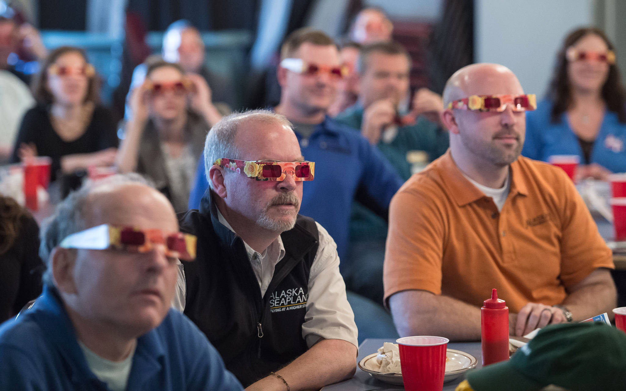 Attendees of the Juneau Chamber of Commerce luncheon don &ldquo;rose-colored glasses&rdquo; to view economic data presented by Brian Holst, executive director of the Juneau Economic Development Council at the Moose Lodge on Thursday, Sept. 28, 2017. (Michael Penn | Juneau Empire)