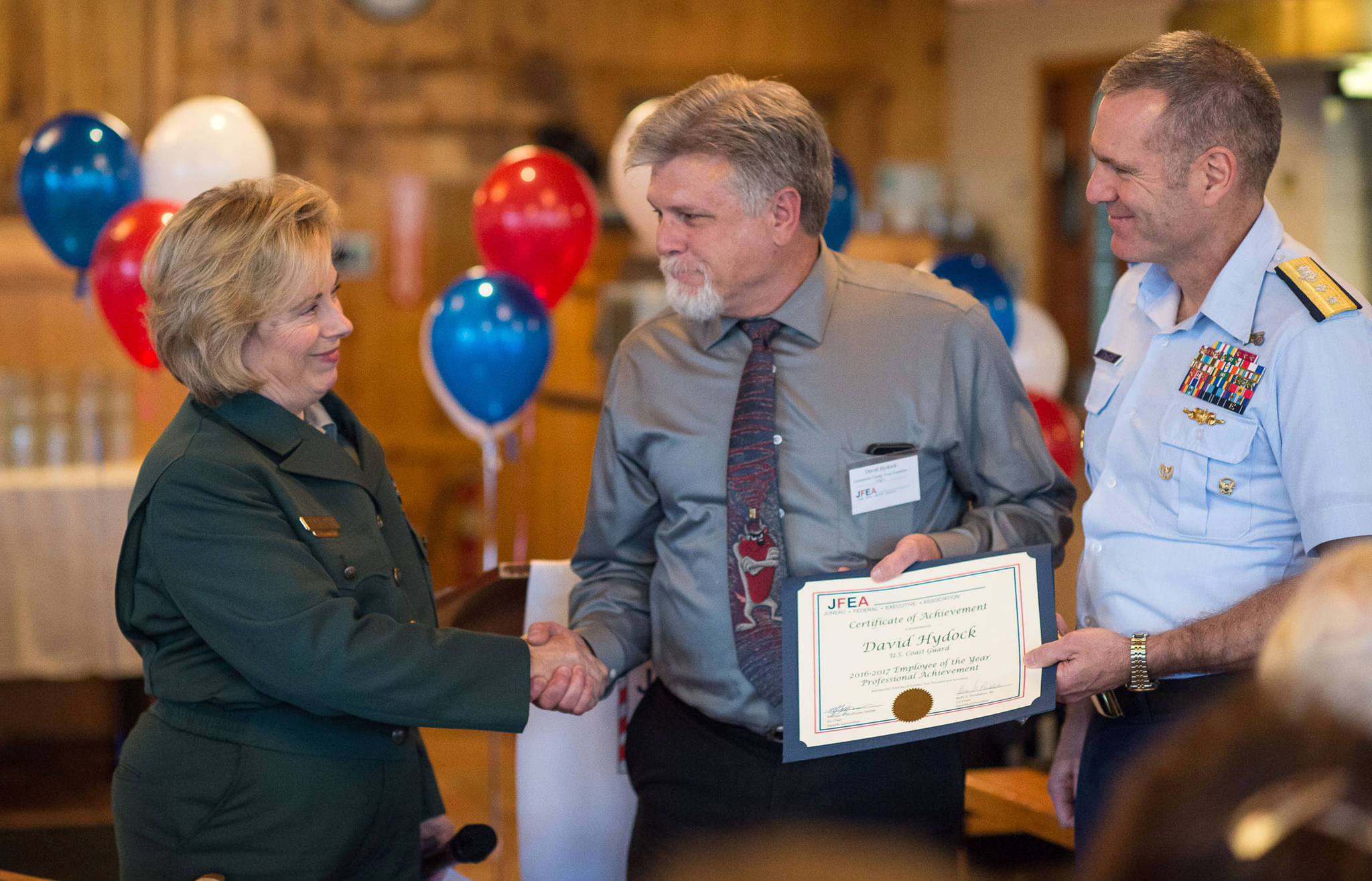David Hydock, center, is presented with the Professional Achievement Award by Regional Forester Beth Pendleton and Rear Admiral Michael McAllister, Commander of the U.S. Coast Guard’s 17th District, at the Juneau Federal Executive Association’s 2016-2017 Federal Employee of the Year Award Banquet and Ceremony at the Twisted Fish on Tuesday, Oct. 3, 2017. (Michael Penn | Juneau Empire)