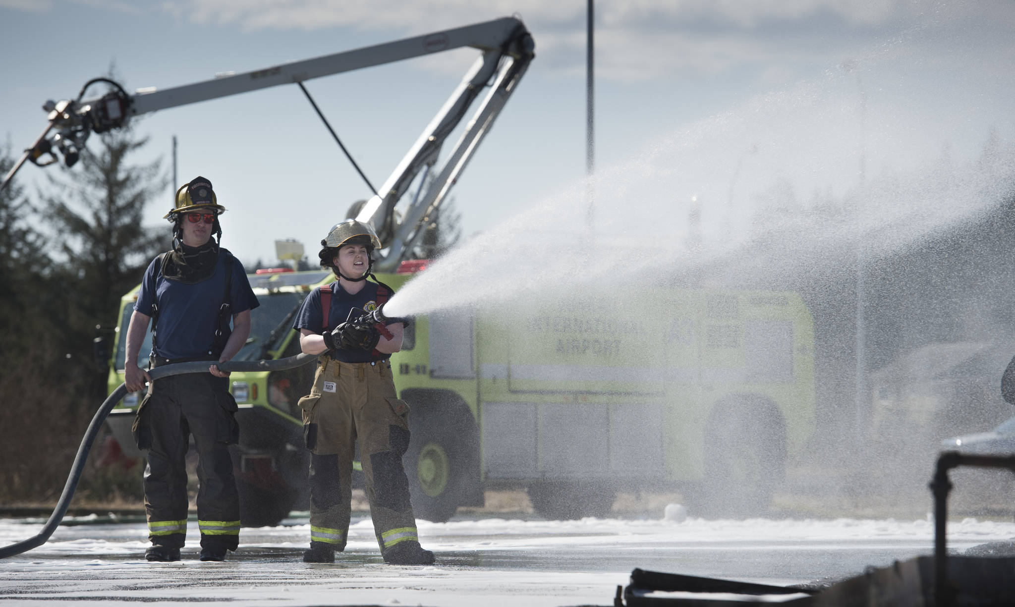 Firefighters Krista Telnes, right, and Dave Edmunds of Capital City Fire/Rescue washdown foam leftover from their airport rescue firefighting skills training at the Hagevig Regional Fire Training Center on Thursday, April 13, 2017. October is Fire Prevention Month in Alaska, and CCFR will offer tours of their facilities. (Michael Penn | Juneau Empire)