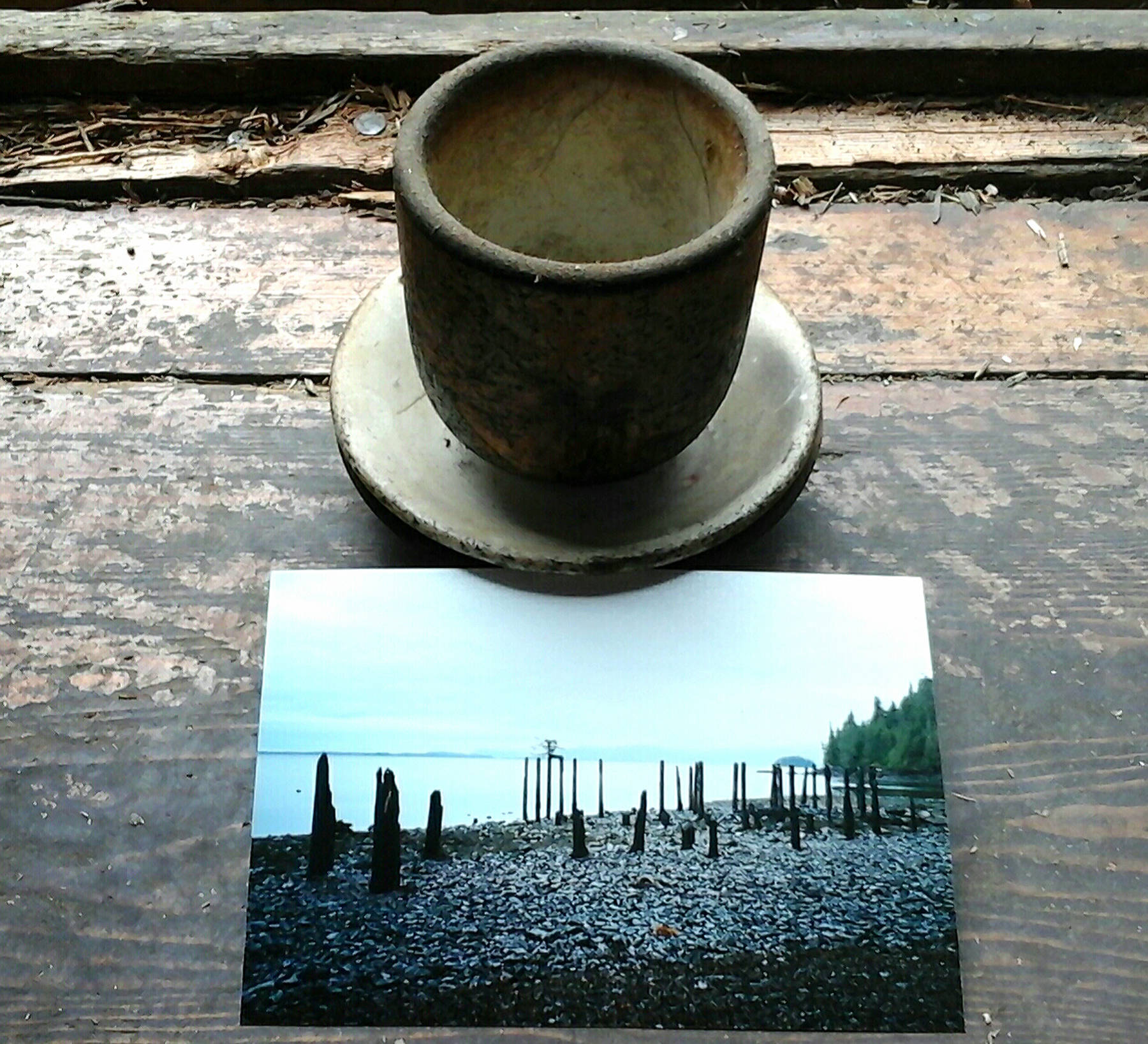 Pottery from the ruins of the cannery with a photo of the burned pilings that supported the cannery. Photo by Tara Neilson.