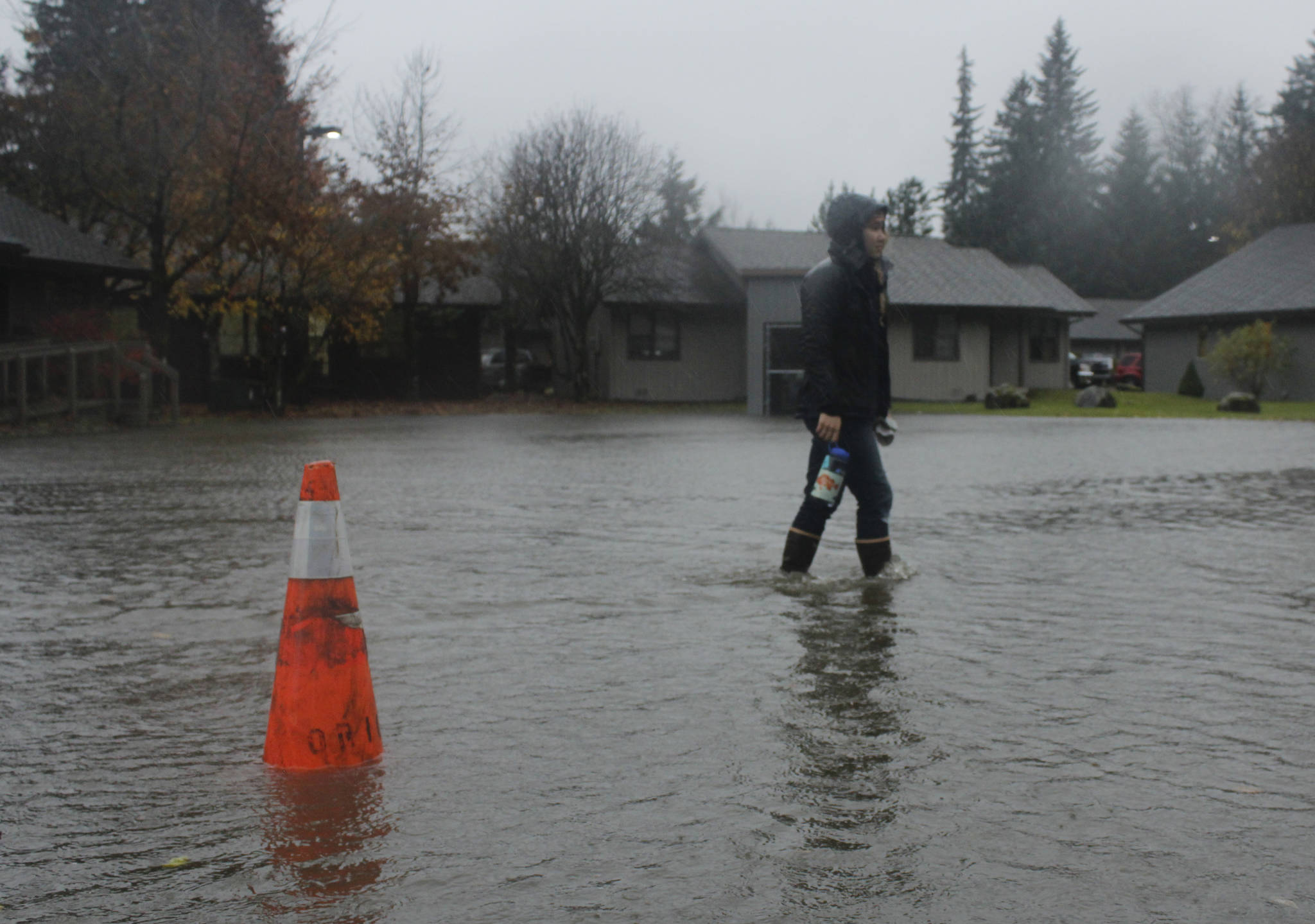 Juneau resident Amy Jenson walks through a flooded parking lot at the Jordan Creek Condominiums on the way to a chiropractor appointment on Friday, Oct. 27, 2017. (Alex McCarthy | Juneau Empire)