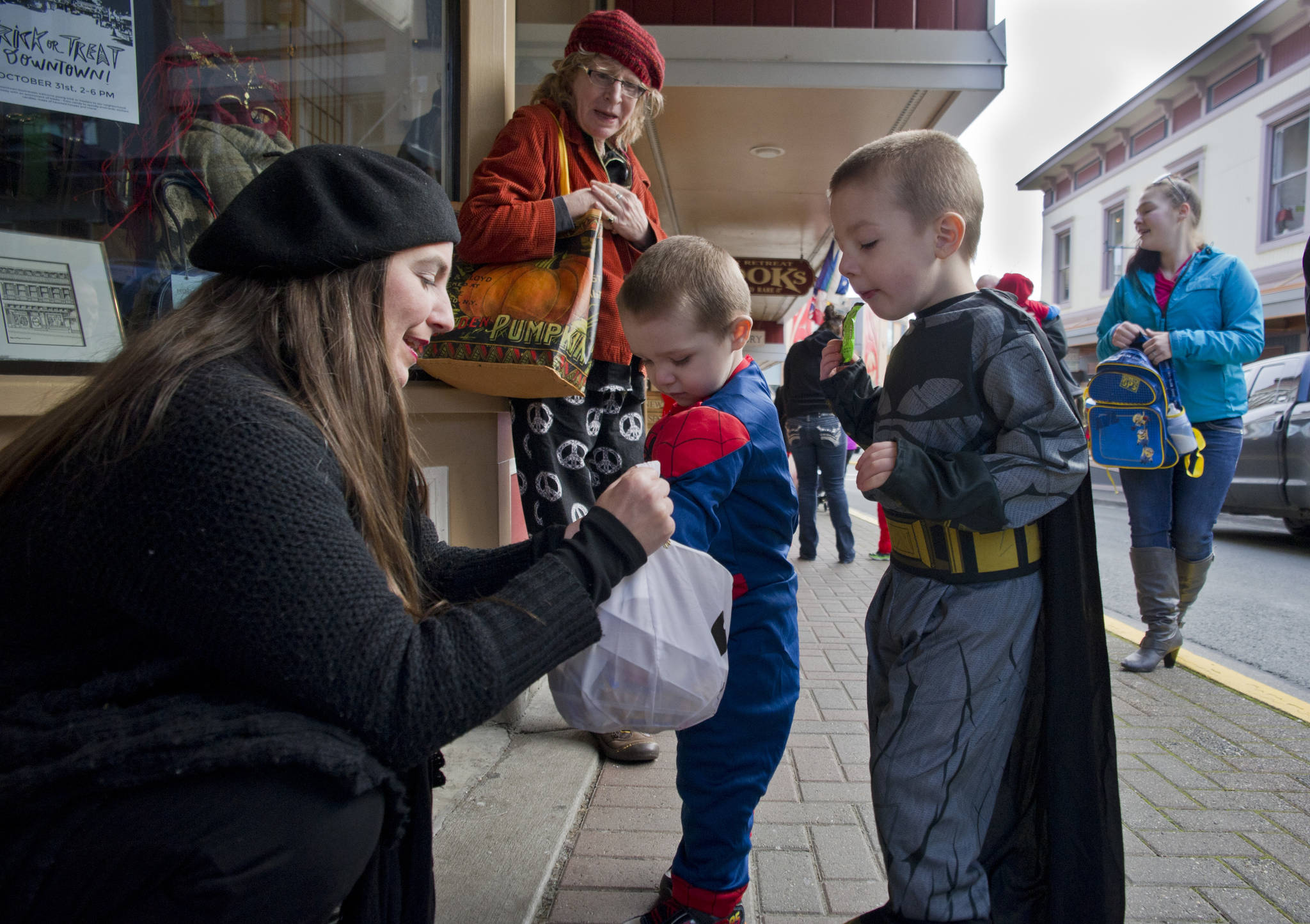 In this Oct. 31, 2016 photo, Lisa Ryals, owner of Lisa Davidson’s Boutique, hands out candy to trick-or-treaters Kyesin Davidson, 4, right, and his brother, CJ, for Halloween. (Michael Penn | Juneau Empire File)