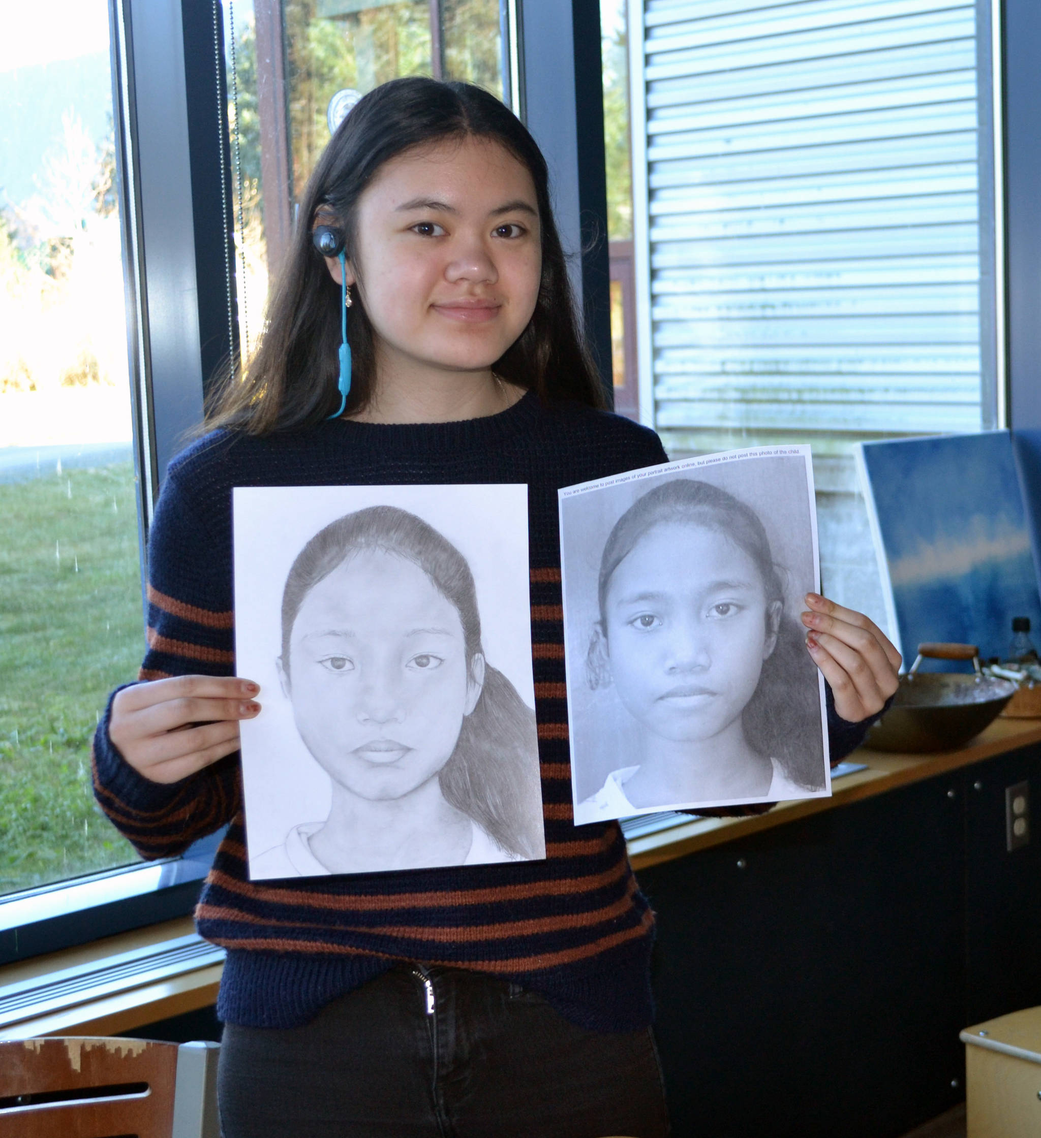 Thunder Mountain High School junior Tianah Sangster poses with portraits she made as part of the Memory Project. The project sends portraits to children in distress all over the world, giving them a keepsake. (Photo courtesy of Angela Imboden)