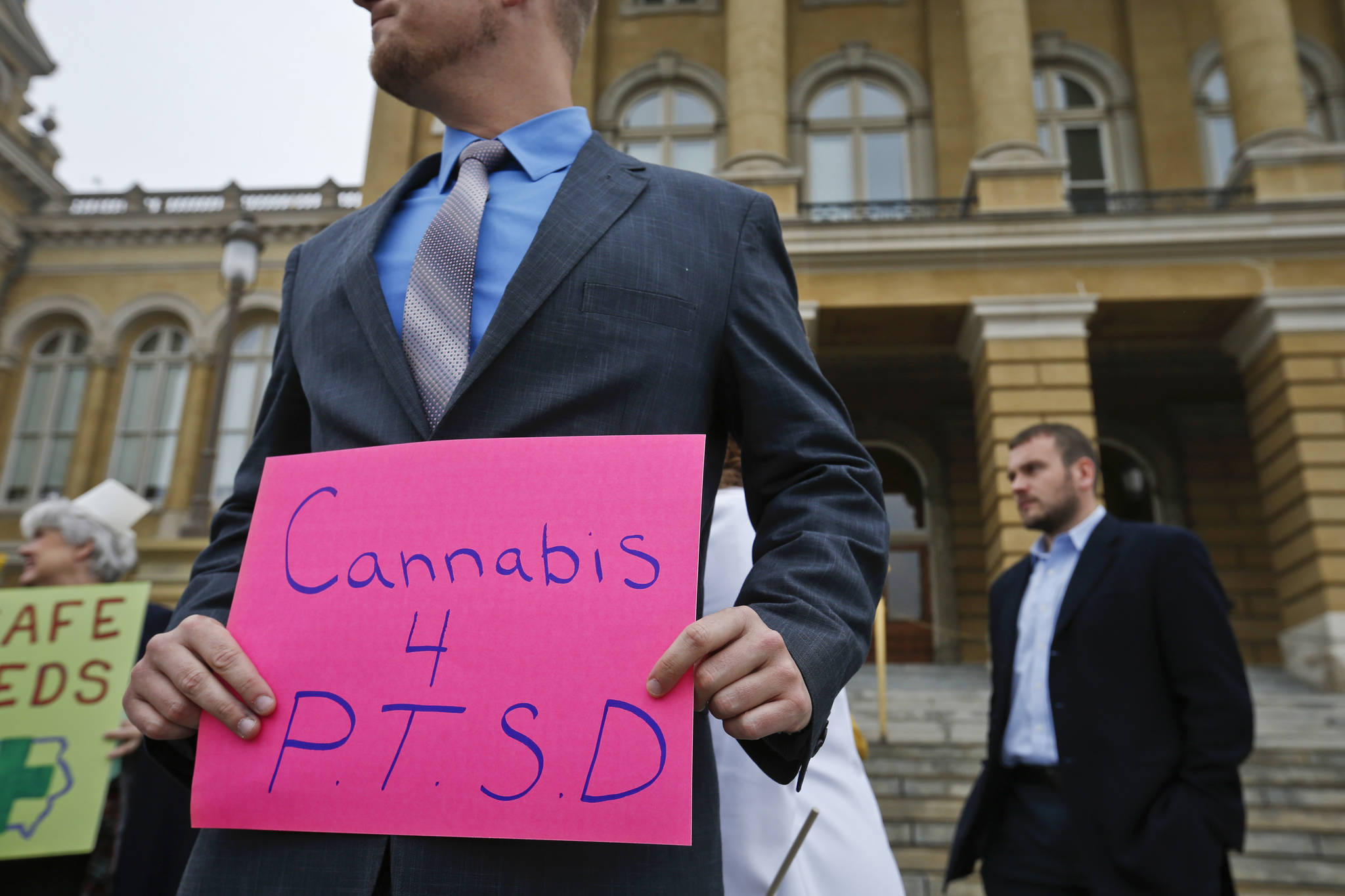 In this Tuesday, April 7, 2015 photo, a Marine veteran holds a sign to show support for cannabis for post traumatic stress disorder sufferers, outside the State Capitol in Des Moines, Iowa. Twenty-eight states plus the District of Columbia have enabled the use of marijuana to treat PTSD, and the number has doubled just in the last two years amid increasingly visible advocacy from veterans’ groups. (Michael Zamora | The Des Moines Register File)