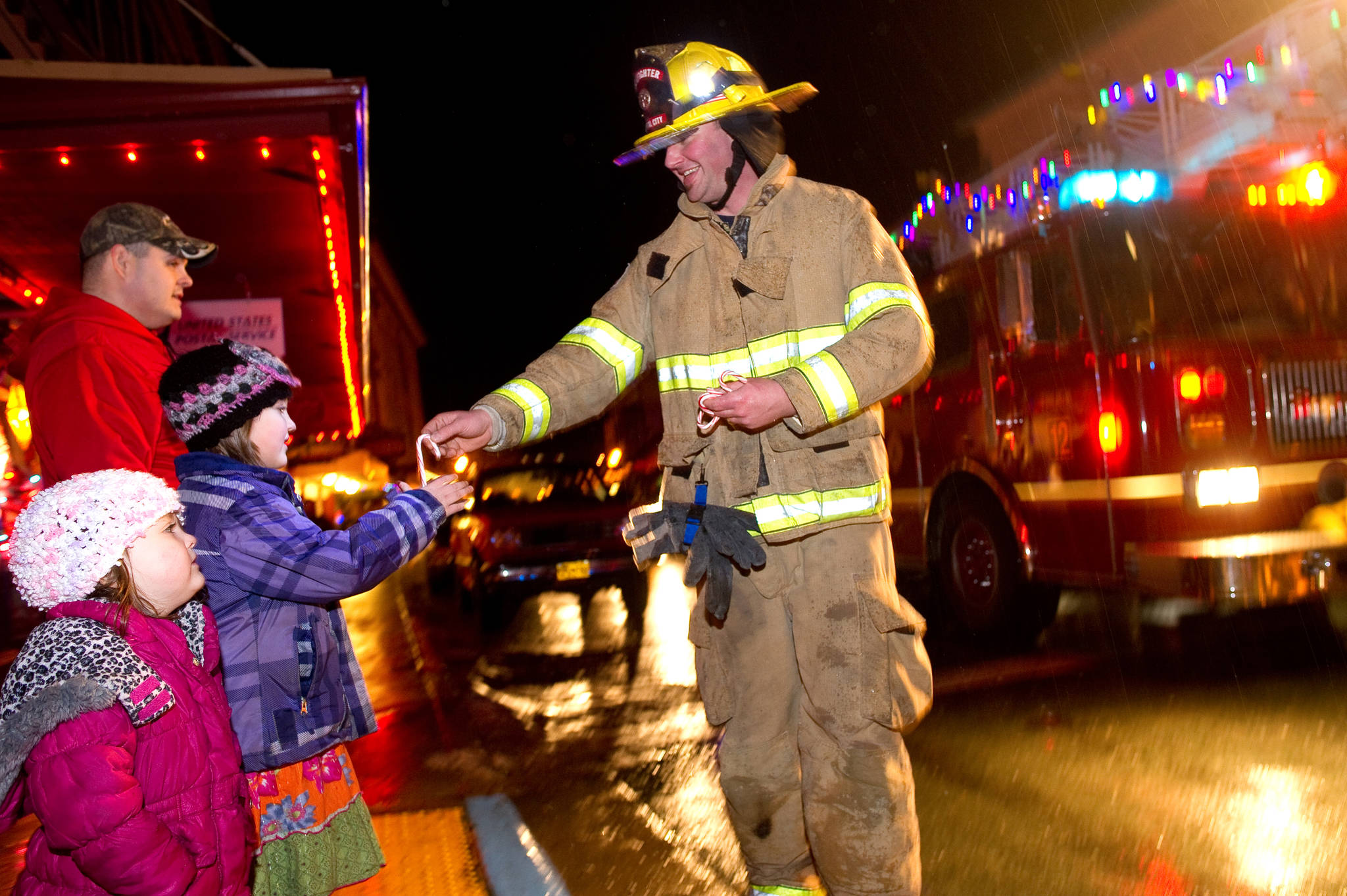 In this file photo, Capital City Fire and Rescue firefighter David Edmunds hands out candle canes to Joanna Magalotti, 6, and her sister, Joella, 3, as firemen make their way through town in December 2012 as part of their annual “Santa on a Fire Truck” event in Juneau and Douglas. (Michael Penn | Juneau Empire)