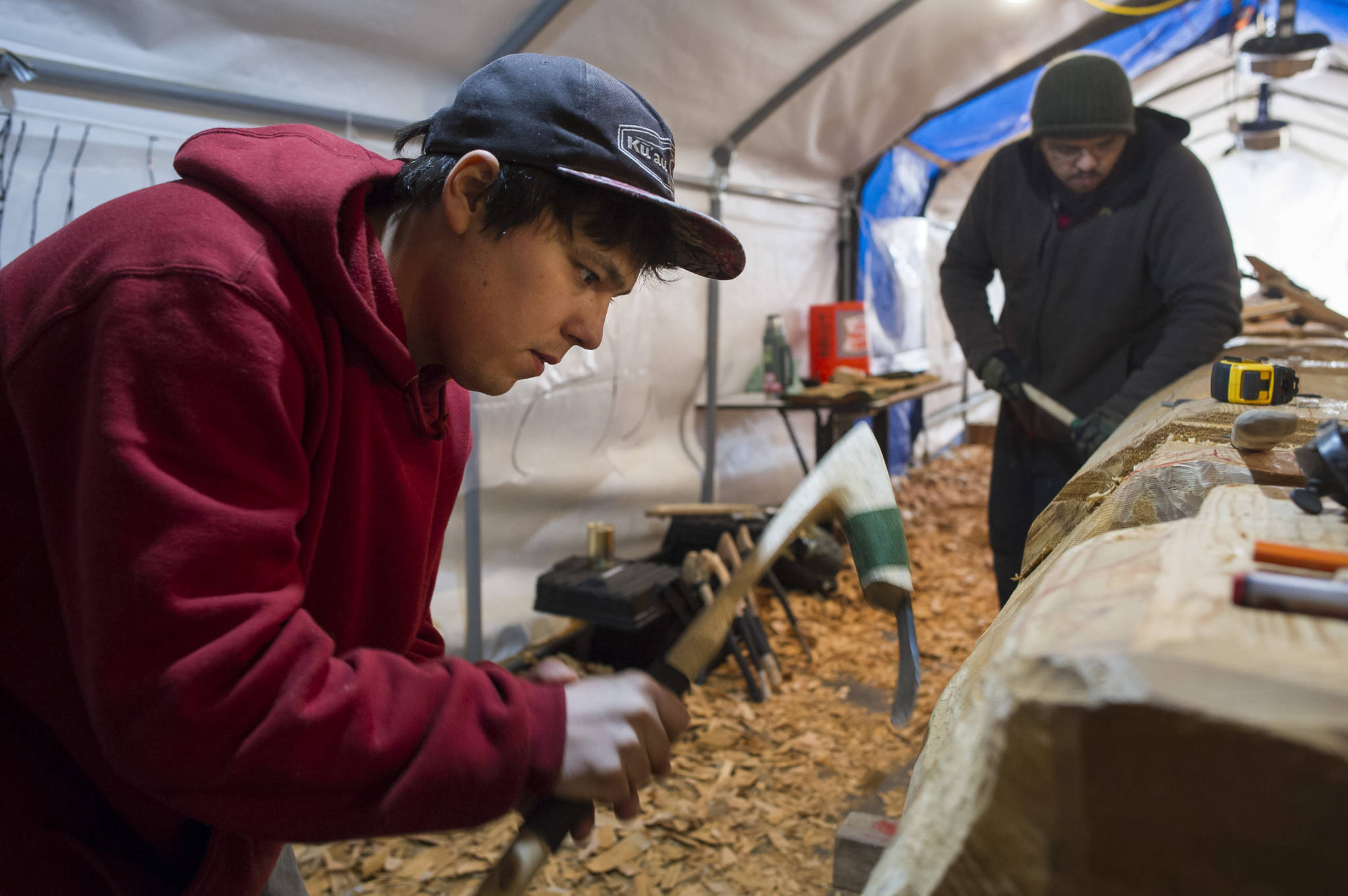 Carvers Lee Burkhart, left, and Herb Sheakley work on the Wolf Totem Pole at Harborview Elementary School on Tuesday, Dec. 5, 2017. (Michael Penn | Juneau Empire)