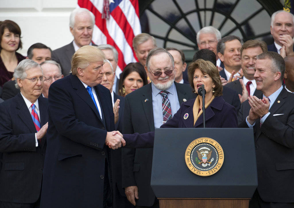 President Donald Trump shakes hands with Sen. Lisa Murkowski, R-Alaska, as she speaks during an event on the South Lawn of the White House in Washington, Wednesday, Dec. 20, 2017, to acknowledge the final passage of tax overhaul legislation by congress. Also on stage are Senate Majority Leader Mitch McConnell of Ky., Rep. Don Young, R-Alaska, and Sen. Dan Sullivan, R-Alaska, right. (Carolyn Kaster | The Associated Press)